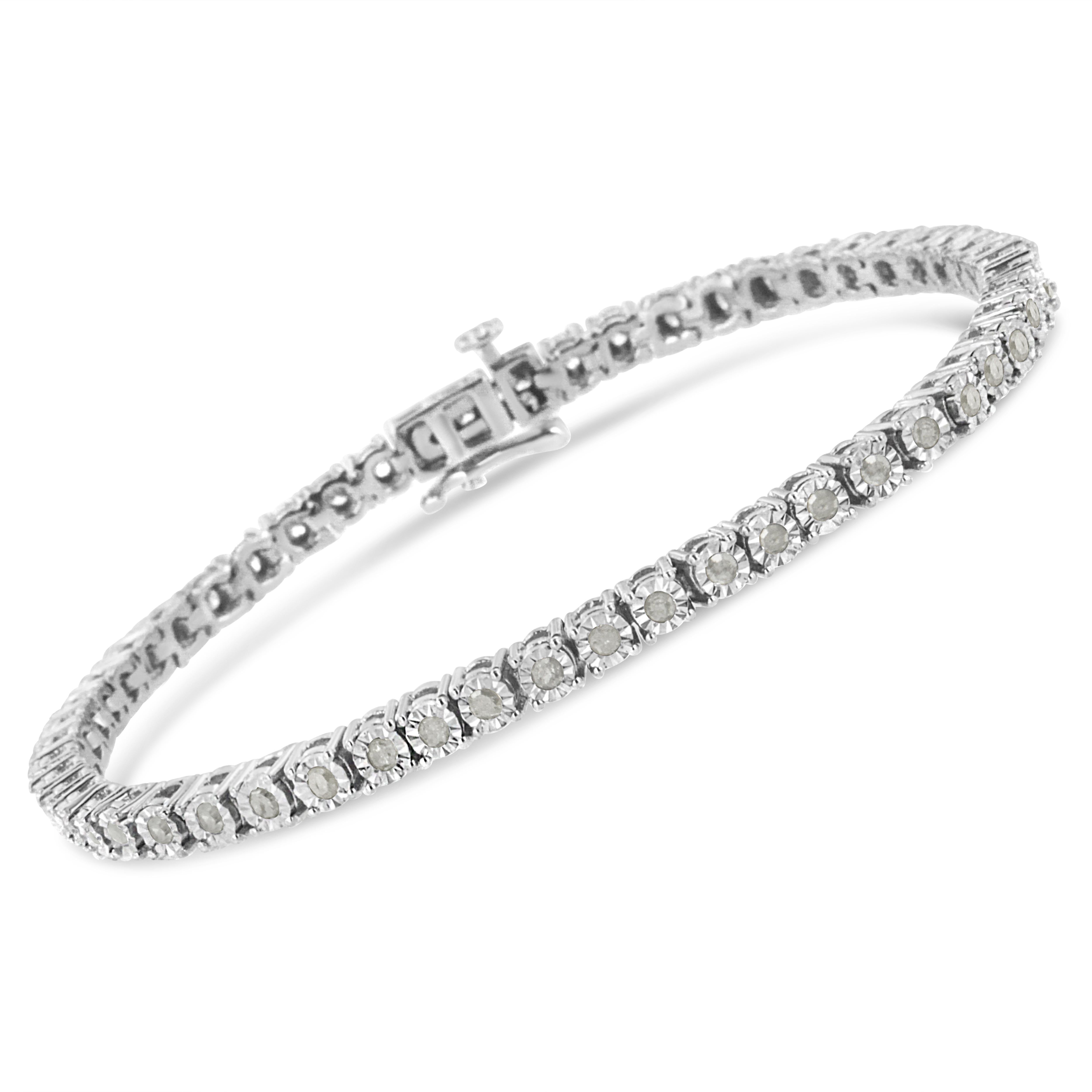 Elegant et intemporel, ce magnifique bracelet de tennis en argent pur 92,5 % est orné de diamants ronds d'un poids total de 1 carat. Le bracelet présente des sertissages uniques avec des plaques miracles qui centrent chaque diamant authentique dans