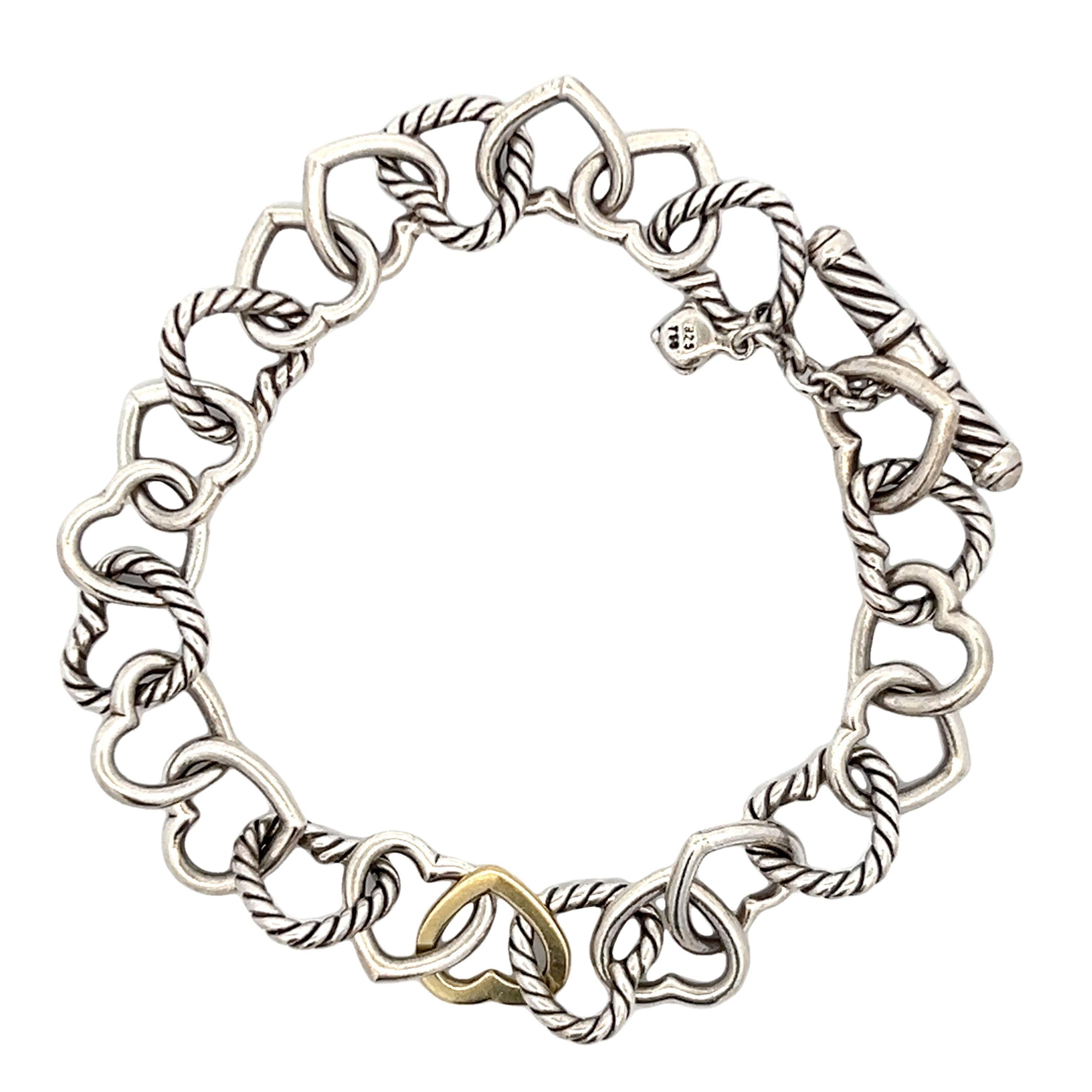 This David Yurman Heart Link Bracelet is a true classic. Crafted from Sterling Silver and 18K yellow gold, this bracelet features a toggle clasp and interlocking hearts. A single sterling silver cable hearts link with smooth silver heart links in an