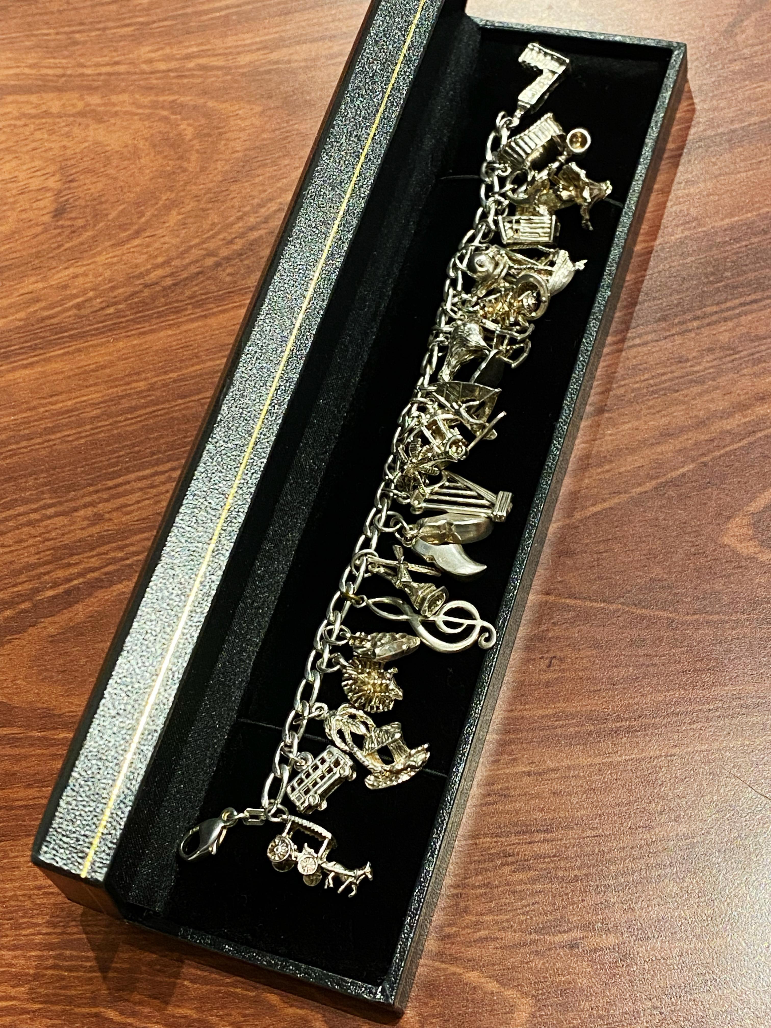 This Magnificent Charm Bracelet
is crafted in 925 Sterling Silver

Featuring 24 charms (all performed in 925 Silver):

Horse & carriage, Double storey bus, Palm tree & hut 
Hedgehog, Sailing boat, Treble-clef
Mill, Shoes, Harp
Palm tree, Old car,