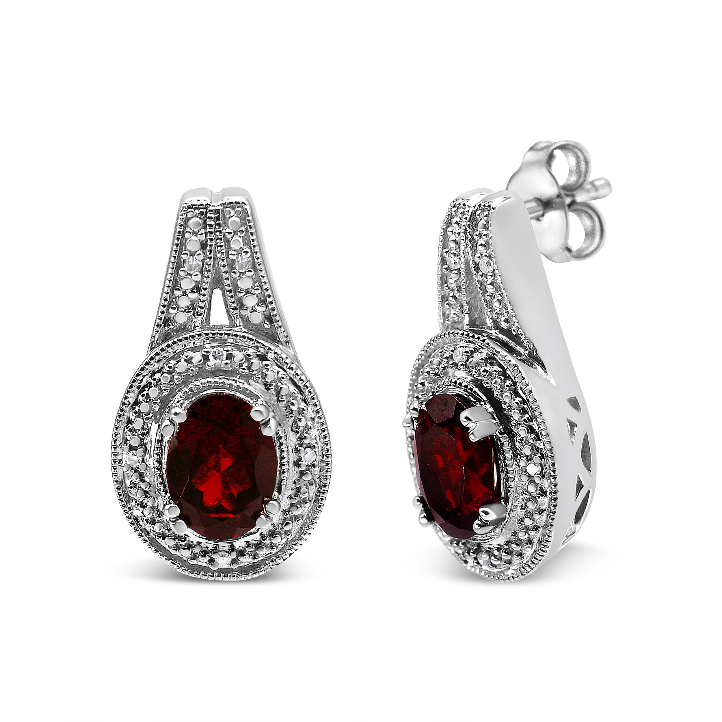 Exuding a regal charm in deep red, this pair of fashion stud earrings is simply elegant. The bold 8*6mm oval-shaped garnet gemstone is surrounded with a pretty milgrain design motif and round white accent diamonds of approximate I-J color and I1-I2