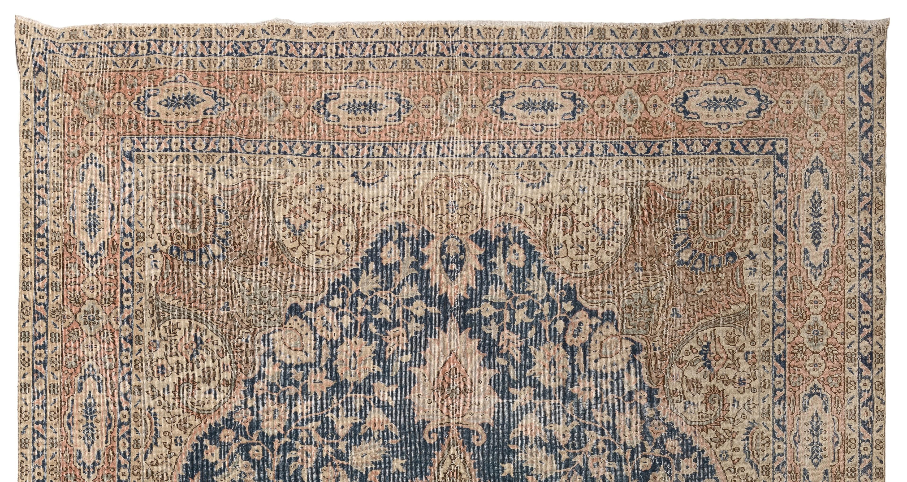 Un grand tapis vintage très finement noué à la main en Turquie dans une palette de couleurs beige pierre, rose saumon, bleu clair et bleu marine. Le motif complexe est très habilement exécuté, du médaillon curviligne au champ de forme similaire dans