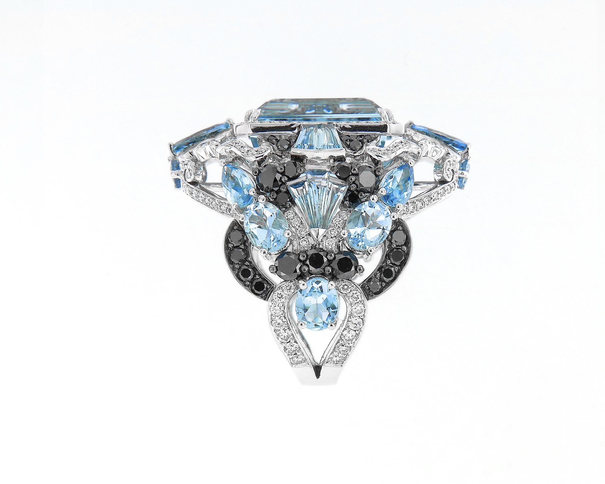 This stunning 9.27 carat emerald-cut baby blue Aquamarine makes you feel like royalty. The already impressive centre stone is further indulged by kisses of aquamarine with black and white diamonds of various shapes and sizes all over the band.