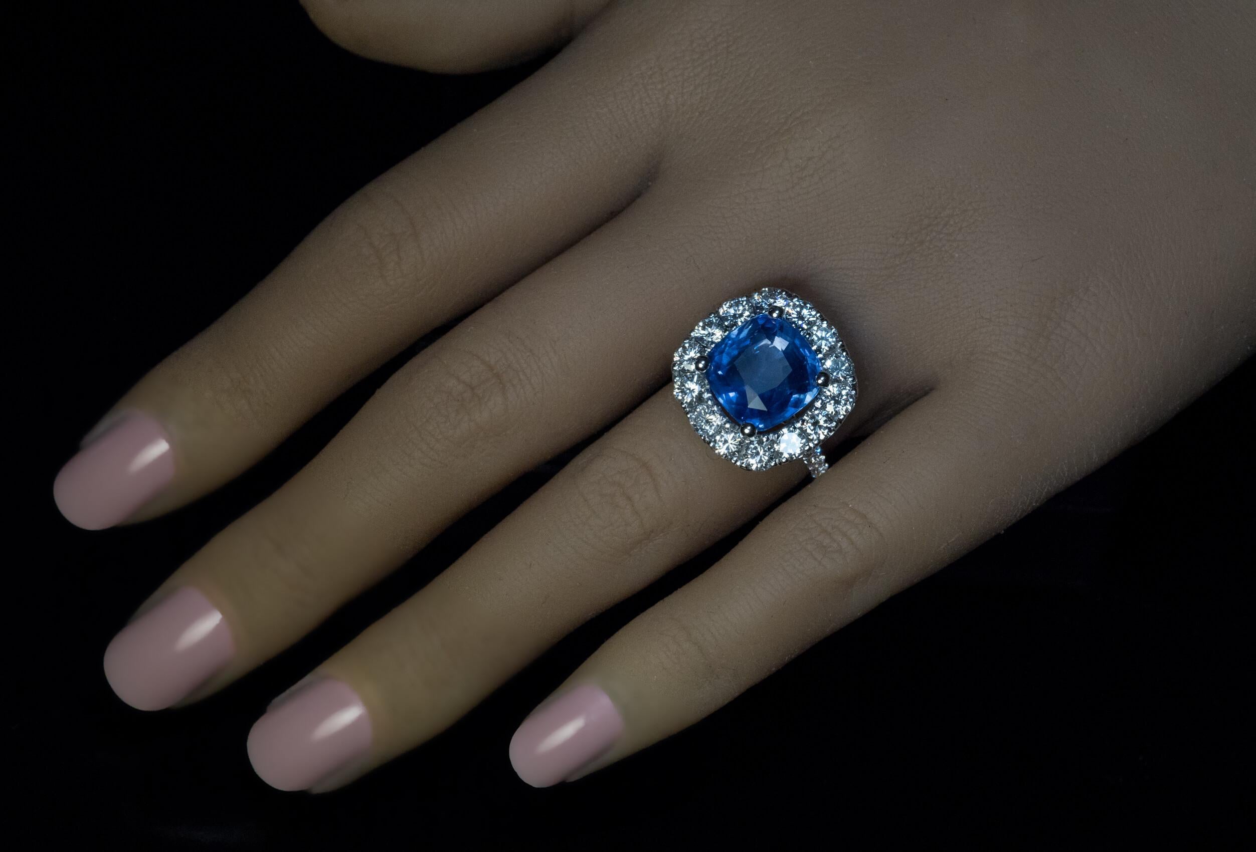This impressive contemporary custom-made 18K white gold cluster ring features a natural unheated 9.33 carat cushion cut blue sapphire. The sapphired is surrounded by bright white brilliant cut diamonds.  Total sapphire weight is 9.33 carats. 