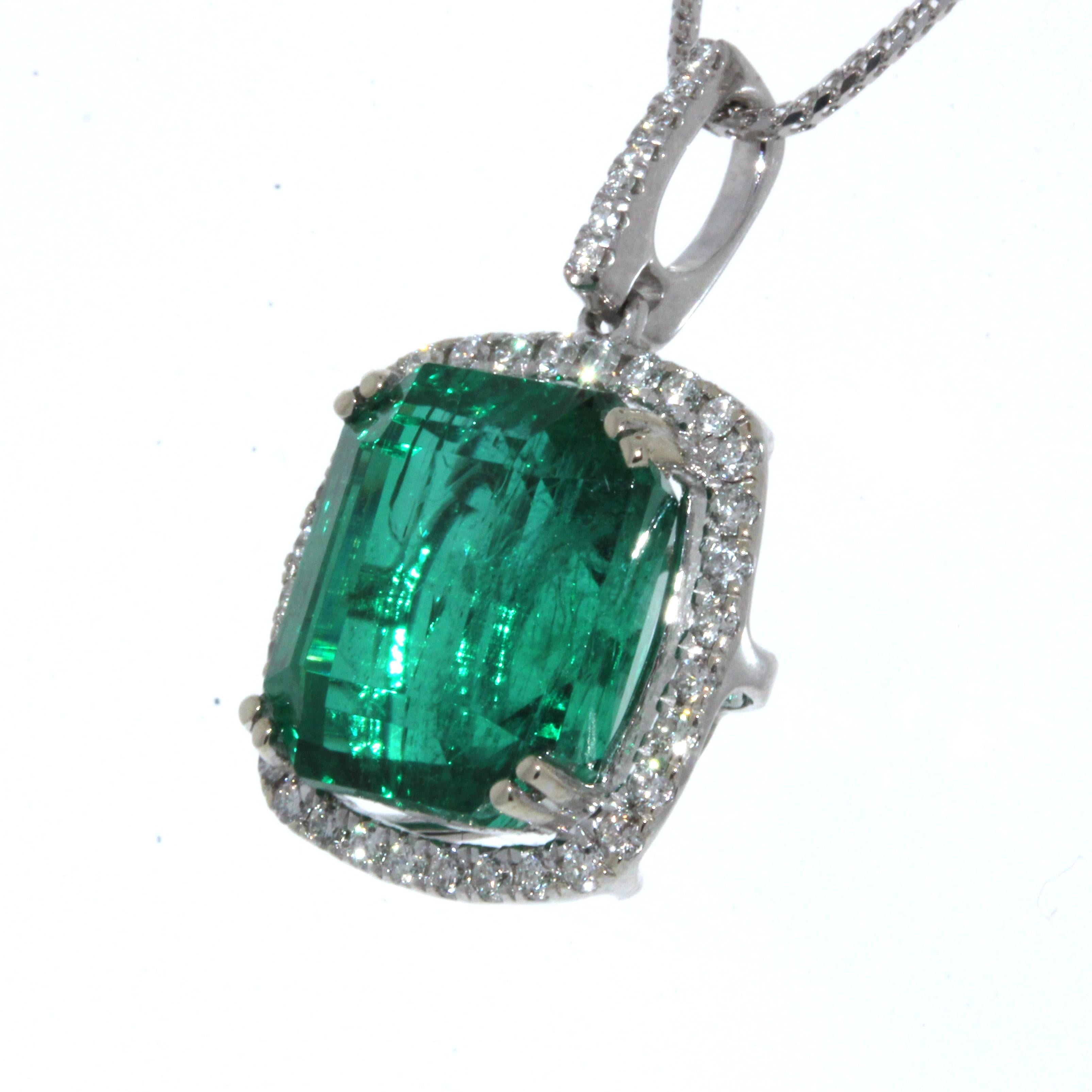 Finish your look with a touch of elegance wearing this gorgeous pendant. One 9.34 carat emerald cut green Emerald takes center stage is surrounded by 39 round brilliant cut diamonds 0.50 carat total weight. The pendant is set in 18K White Gold. This
