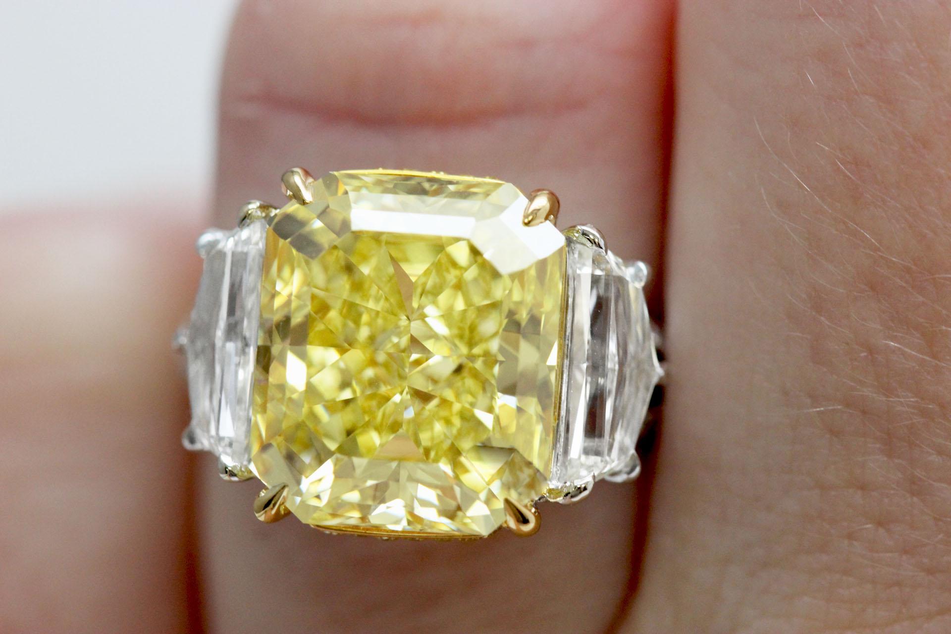 A 9+ carat fancy intense yellow radiant cut diamond three-stone engagement ring on a platinum and gold setting. GIA certified natural 9.37 carat fancy intense yellow radiant diamond (VVS1 Clarity) engagement ring with two epaulet-cut white diamonds