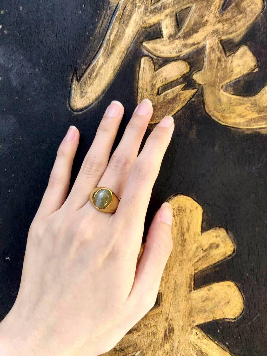 This 18k gold ring boasts rare 9.4 carat cabochon greenish yellow cat's eye chrysoberyl with sharp chatoyancy. The plain raised edge design possesses a feel of modernity which makes this luxury piece remain contemporary.

Cat's Eye Chrysoberyl: