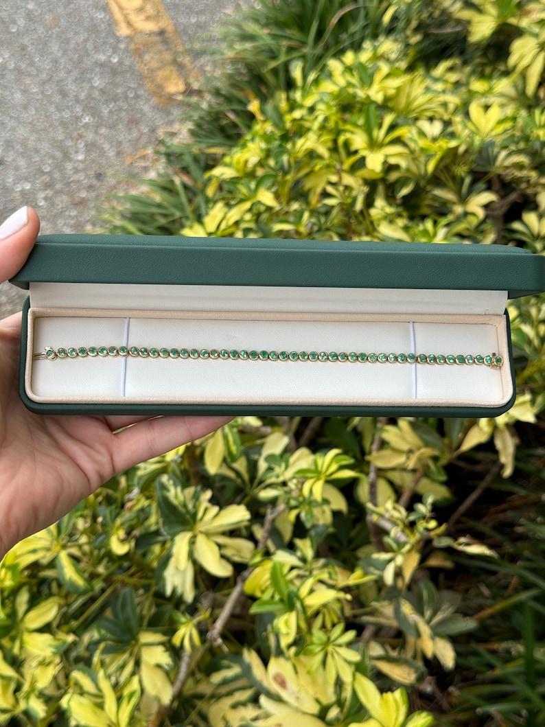 Adorn your wrist with the timeless allure of our Emerald Tennis Bracelet, a graceful expression of sophistication and natural beauty. Crafted in lustrous 14k gold, this bracelet features numerous petite round-cut emeralds, totaling approximately