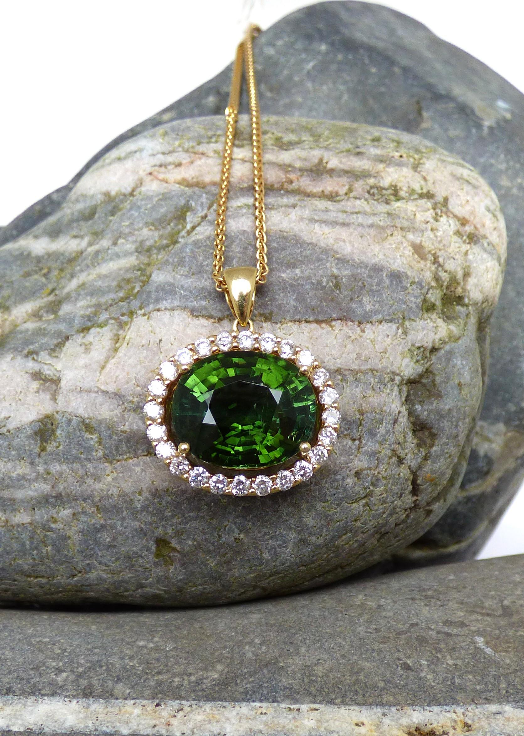 This bright colourful Green Tourmaline sets off this pendant.  The Tourmaline is oval weighs 9.48ct.  It is surrounded by 24 Diamonds with a total Diamond weight of .92ct. This piece is handmade in 18K yellow gold and hallmarked by the Dublin Assay