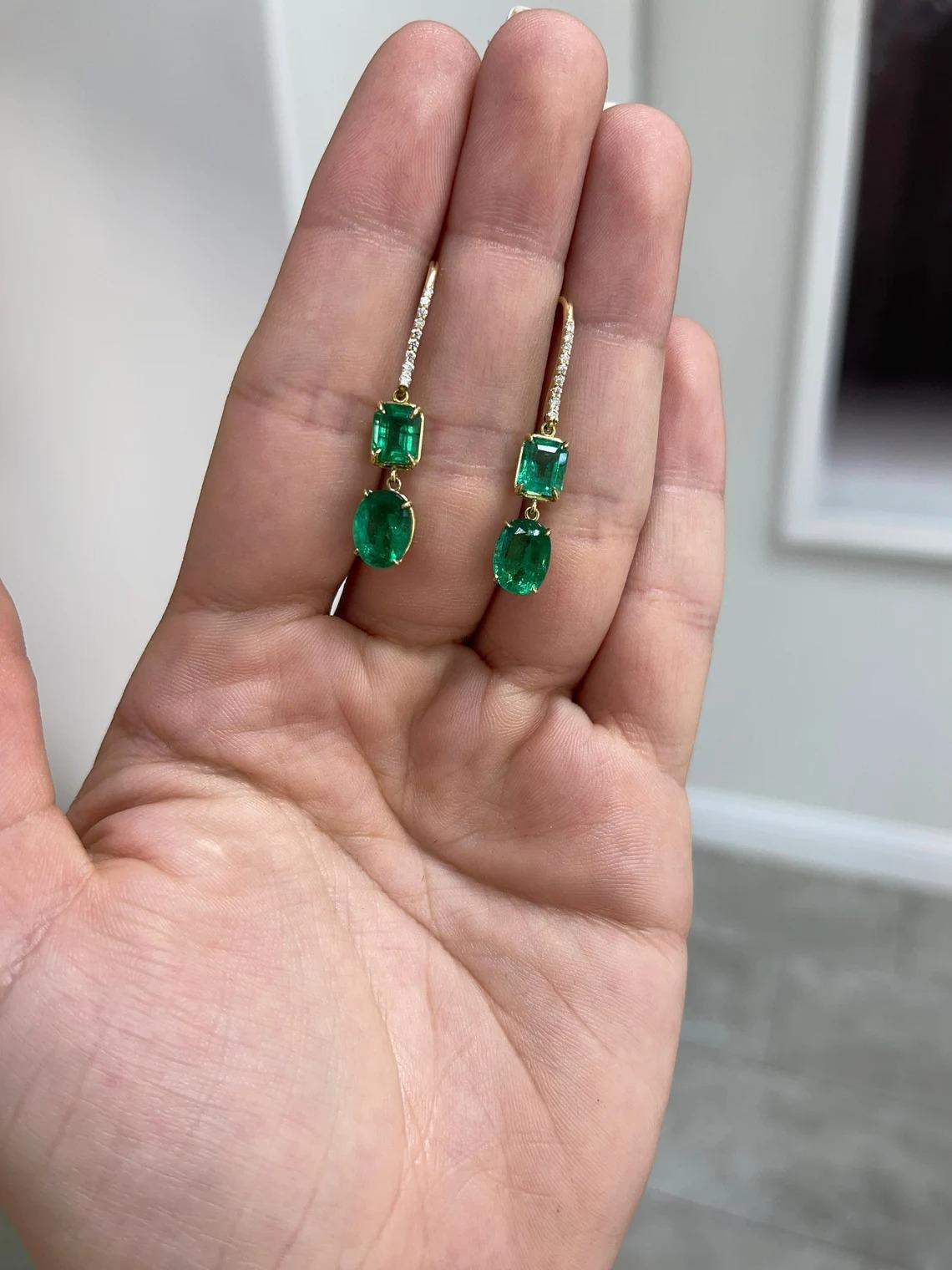 A gorgeous, and fine-quality pair of natural emerald dangle earrings with diamond accents. Both pairs of emerald cut and oval cut emeralds all have remarkable characteristics, such as their vivid dark lush green color with a yellowish-green hue,