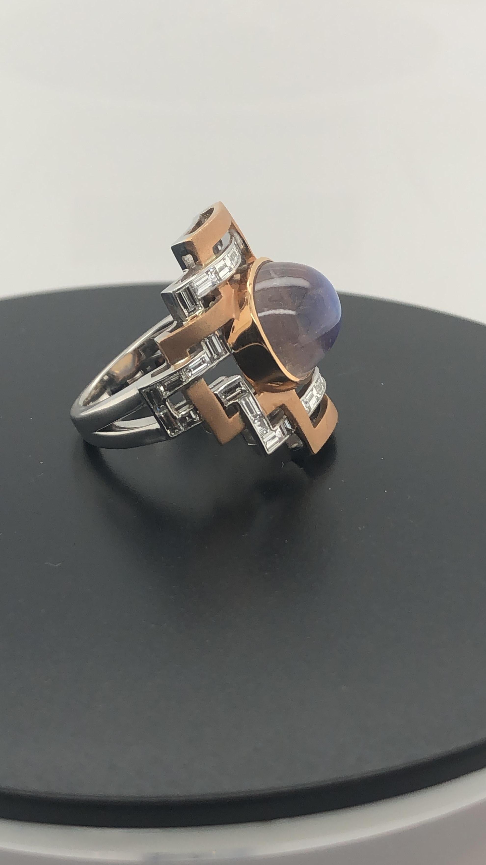 One Hand Crafted Rose and White Gold 9.53 Carat Cushion Cut Moonstone, Bezel Set in Rose Gold and surrounded by 34 Baguette and Carre cut Diamonds weighing 1.45 carats, channel set in white gold, weaving through a rose gold geometric, Art Deco