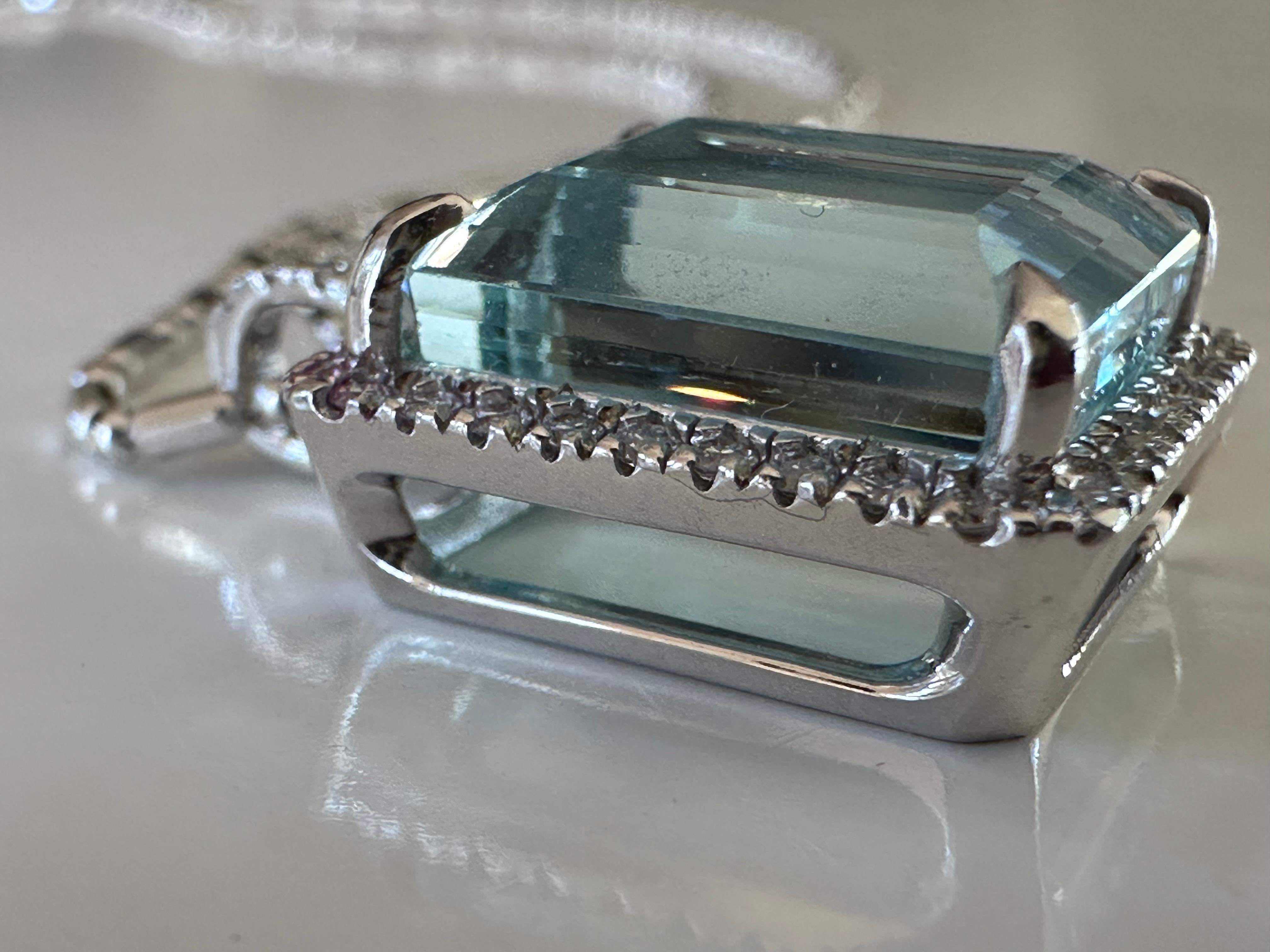 A stunning 9.55-carat emerald-cut light blue aquamarine centers this pendant necklace handcrafted in 14K white gold and surrounded by a halo of forty round diamonds, G color, SI1 clarity totaling 0.34 carats. The necklace measures 18 inches. 

