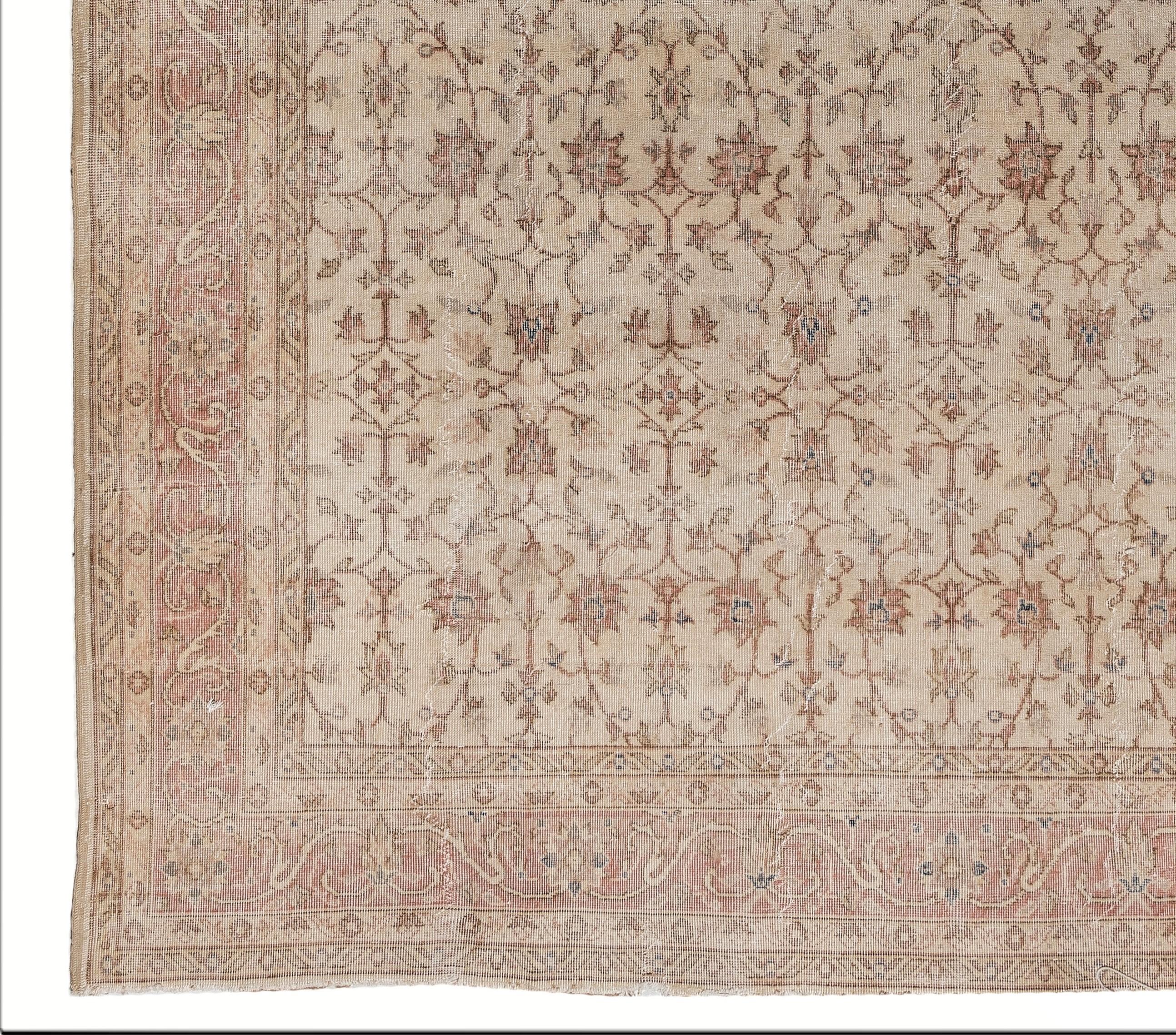 A vintage hand knotted Turkish Oushak rug in a very soft, muted palette of beige, khaki, ecru, tan, fawn a. The rug features two floral medallions at both ends of the field that is filled with symmetrically placed floral vines centered around large