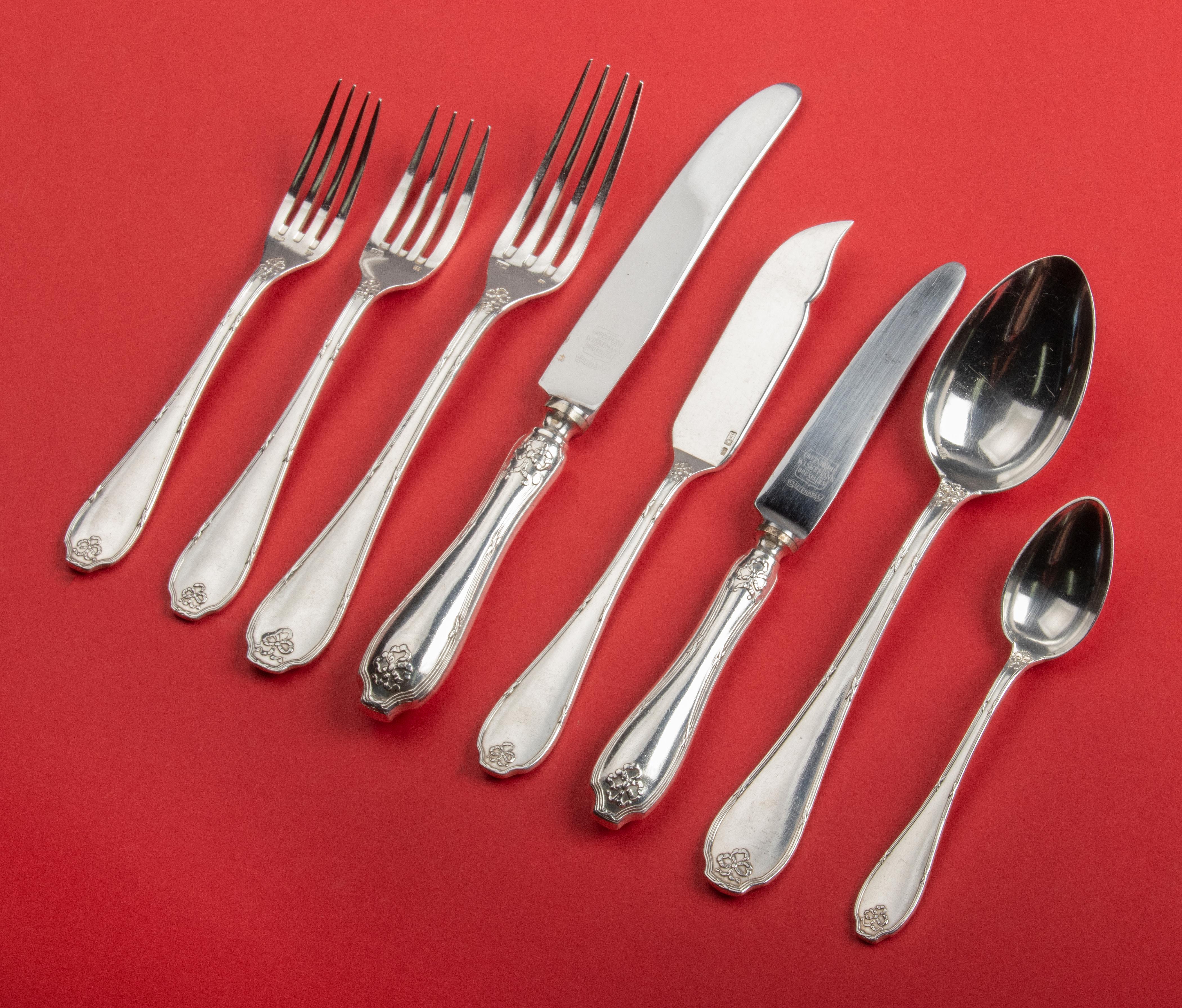 96-Piece silver-plated flatware for 12 people by the Belgian maker Wiskemann. The flatware has refined decorations with ribbons and bows. The set is composed as follows: 12 table knives, 12 table forks, 12 table spoons, 12 lunch knives, 12 lunch