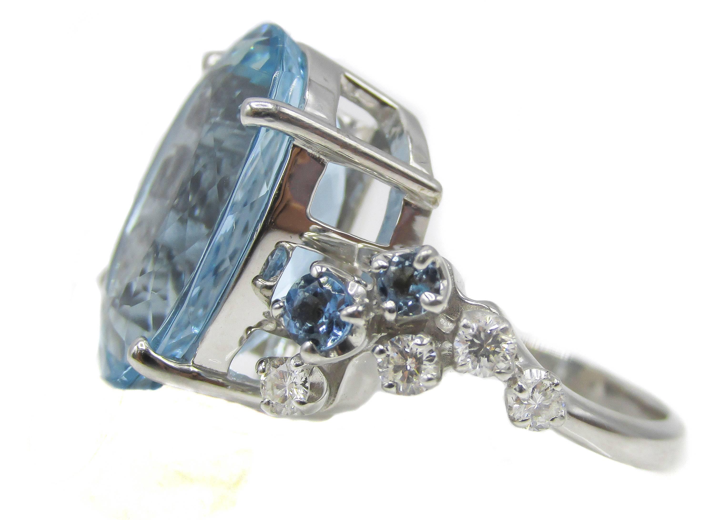 Artistic and lively 18 karat white gold ring centrally set with one extremely brilliant oval sky blue aquamarine weighing 9.65 carats. The shanks of this ring are playfully designed with one side set with 4 round brilliant cut aquamarines and 2