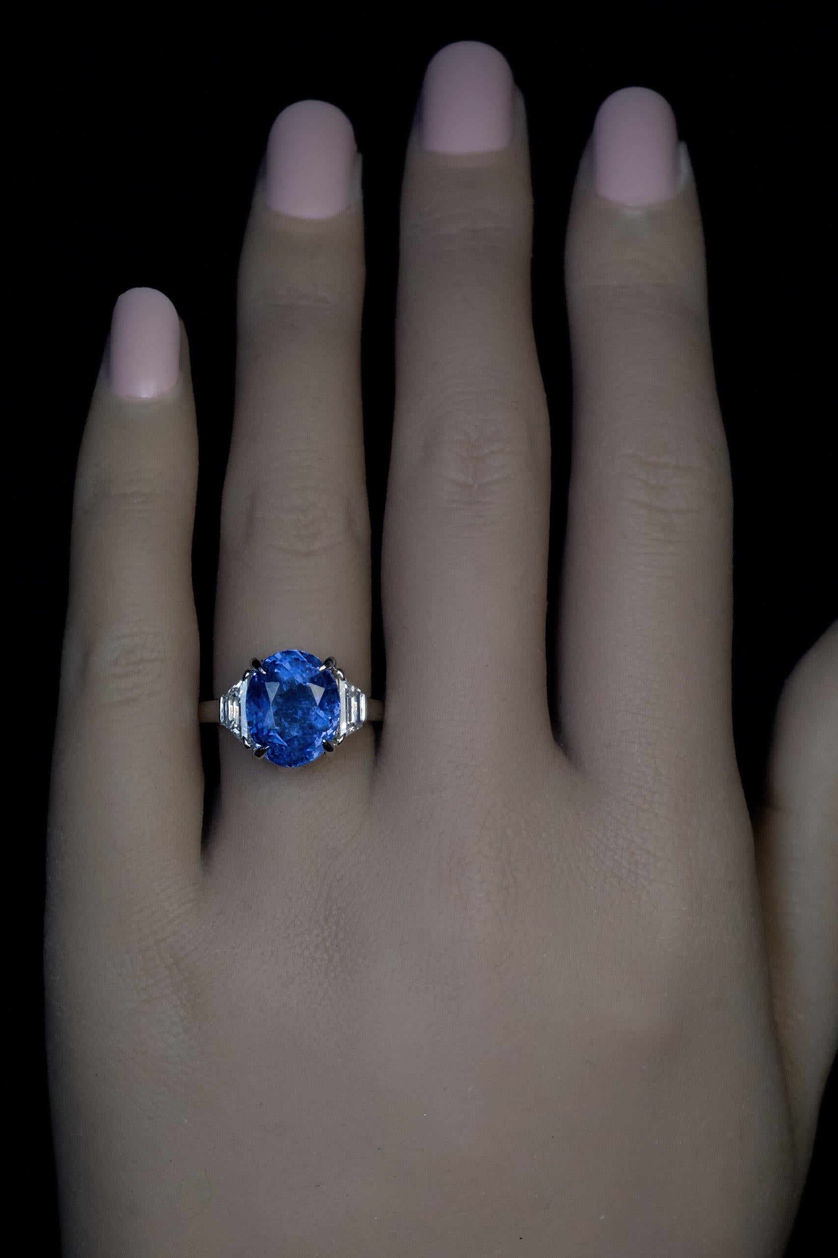 This contemporary custom-made platinum engagement ring features a 9.67 carat natural unheated Ceylon sapphire of a very nice rich medium blue color. The sapphire is flanked by two bright white trapezoid cut diamonds (G color, VS1 / SI2 clarity). 