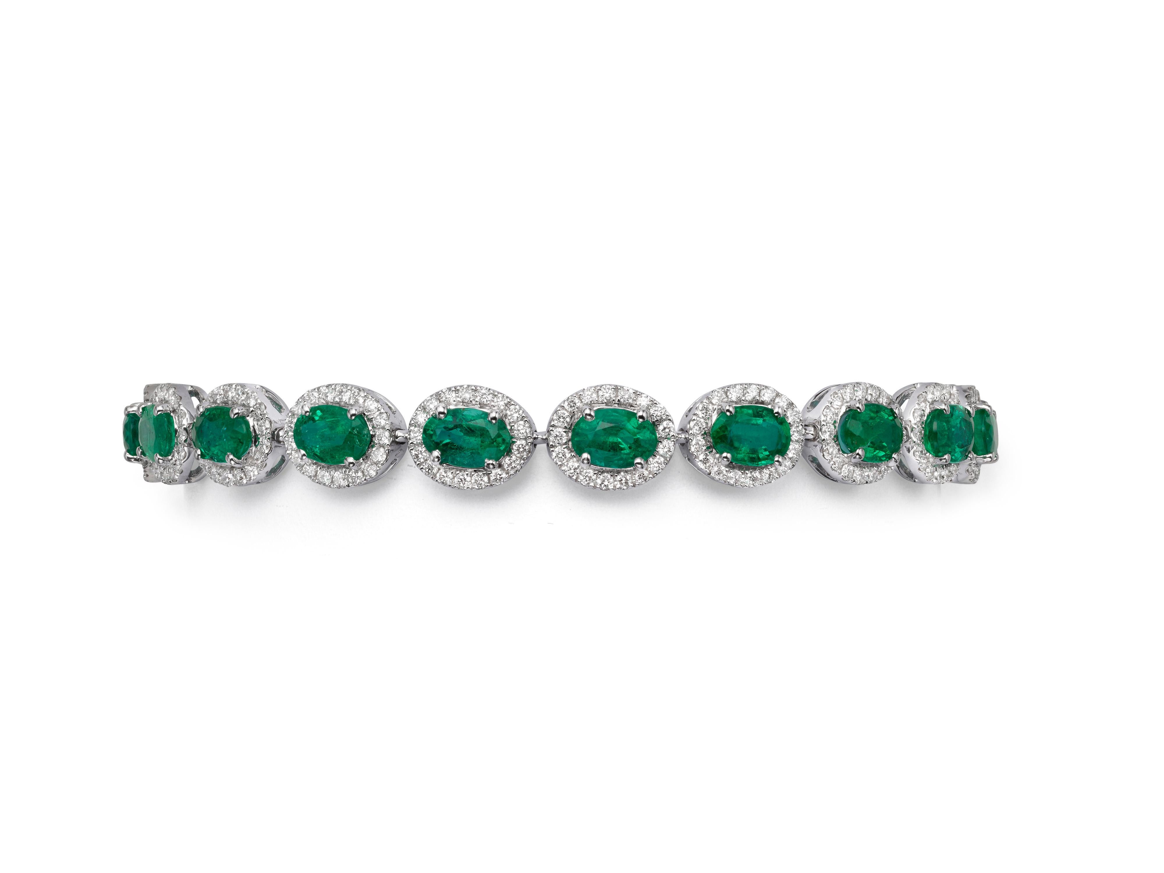 An emerald and diamond bracelet handcrafted from 18K white gold.  An oval green emerald sits in the center of each link and is encircled by a glittering halo of white diamonds.  The vibrant green emeralds have a total weight of 7.84 carats and the