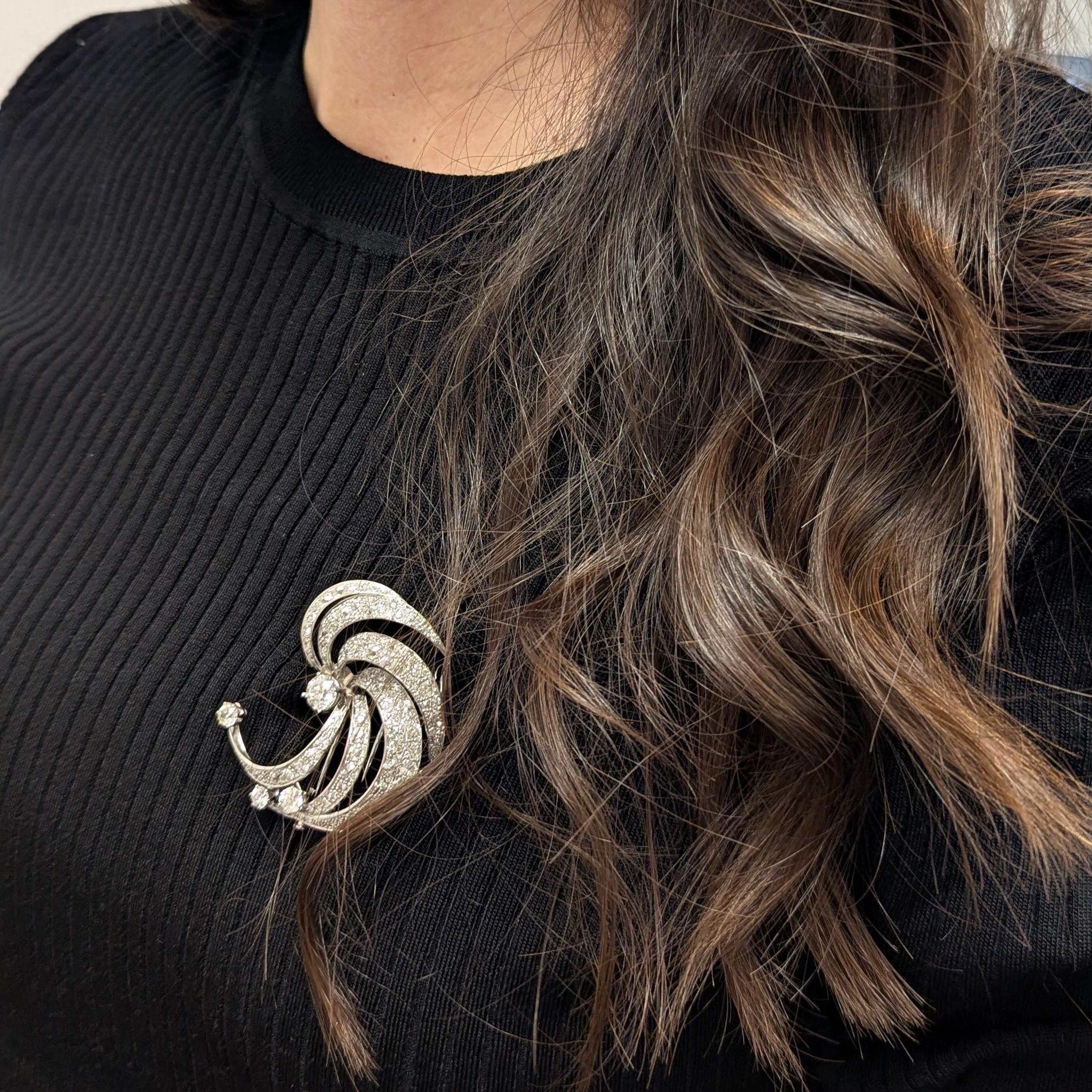 This brooch is designed with six curled old-cut diamond-set curled strands encircling a 1.45 carat European-cut diamond. The remaining diamonds weigh approximately 8.25 carats, all meticulously mounted in 18k white gold. 