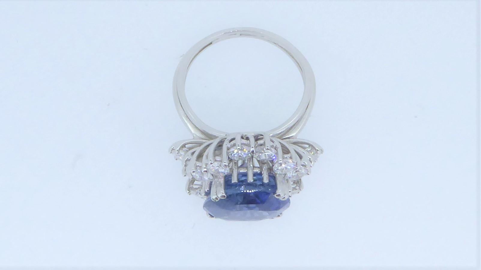 A 9.71 Carat Unheated Burmese Sapphire, Diamond And 18 Carat White Gold Cluster Ring. The oval sapphire with SSEF Certificate, stating it to be from Burma and with no indications of heating. In a surround of white diamonds, totalling approximately 2