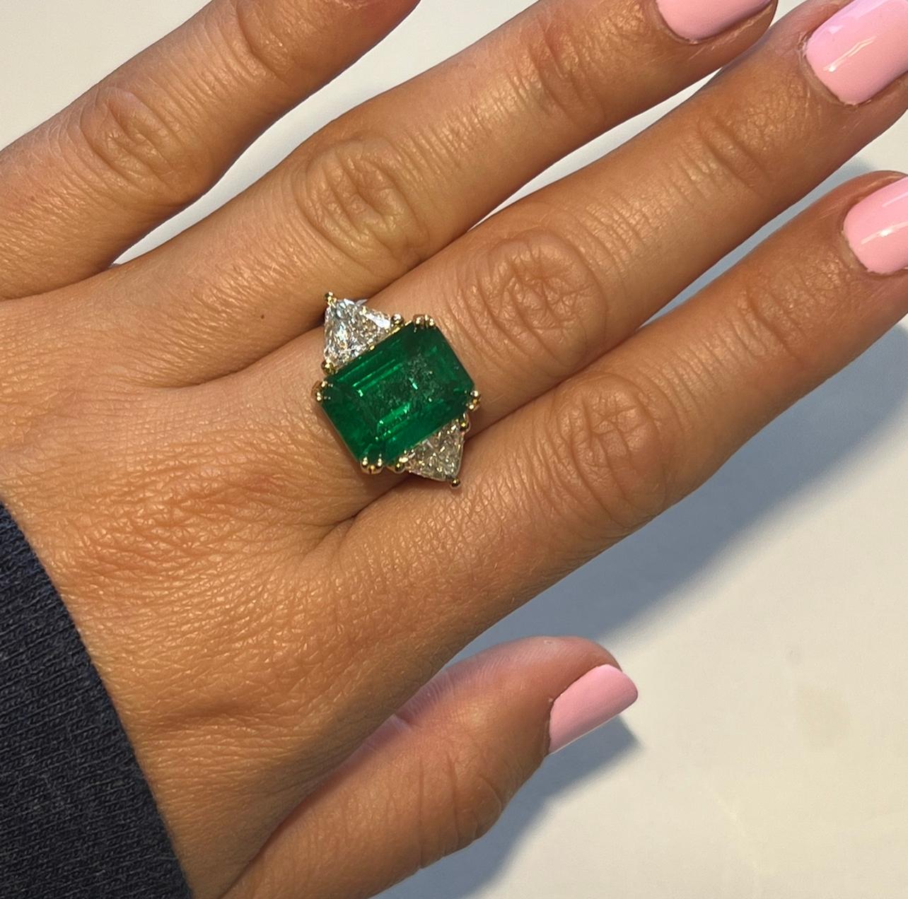 9.72 carats natural Earth Mined Emerald 
Emerald comes with GIA CERT
Emerald measures 13.92 X 10.46 X 8.66mm
1.86 Carats sI1 HI color natural earth mined Trillion Cut diamonds Flanking Center Emerald 
18k Yellow Gold
Made in the USA in Miami,