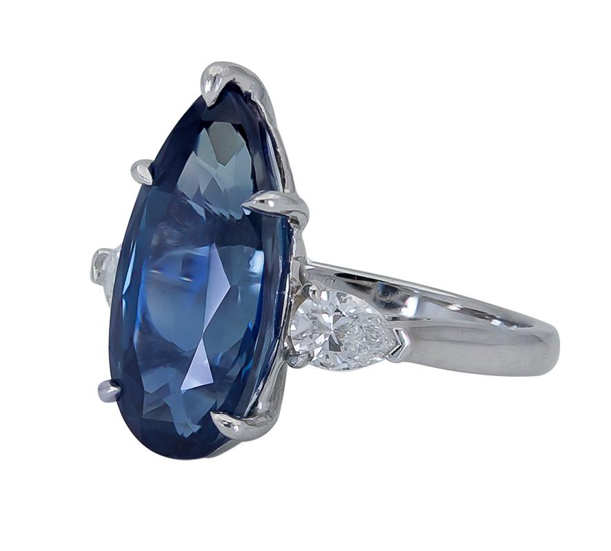 Showcasing an elongated pear shape blue sapphire, flanked by two brilliant pear shape diamonds. Set in a polished platinum mounting. 
Blue sapphire weighs 9.73 carats total.
Diamonds weigh 0.80 carats total.
Size 8 US (sizable)
1.98 cm length x 0.89