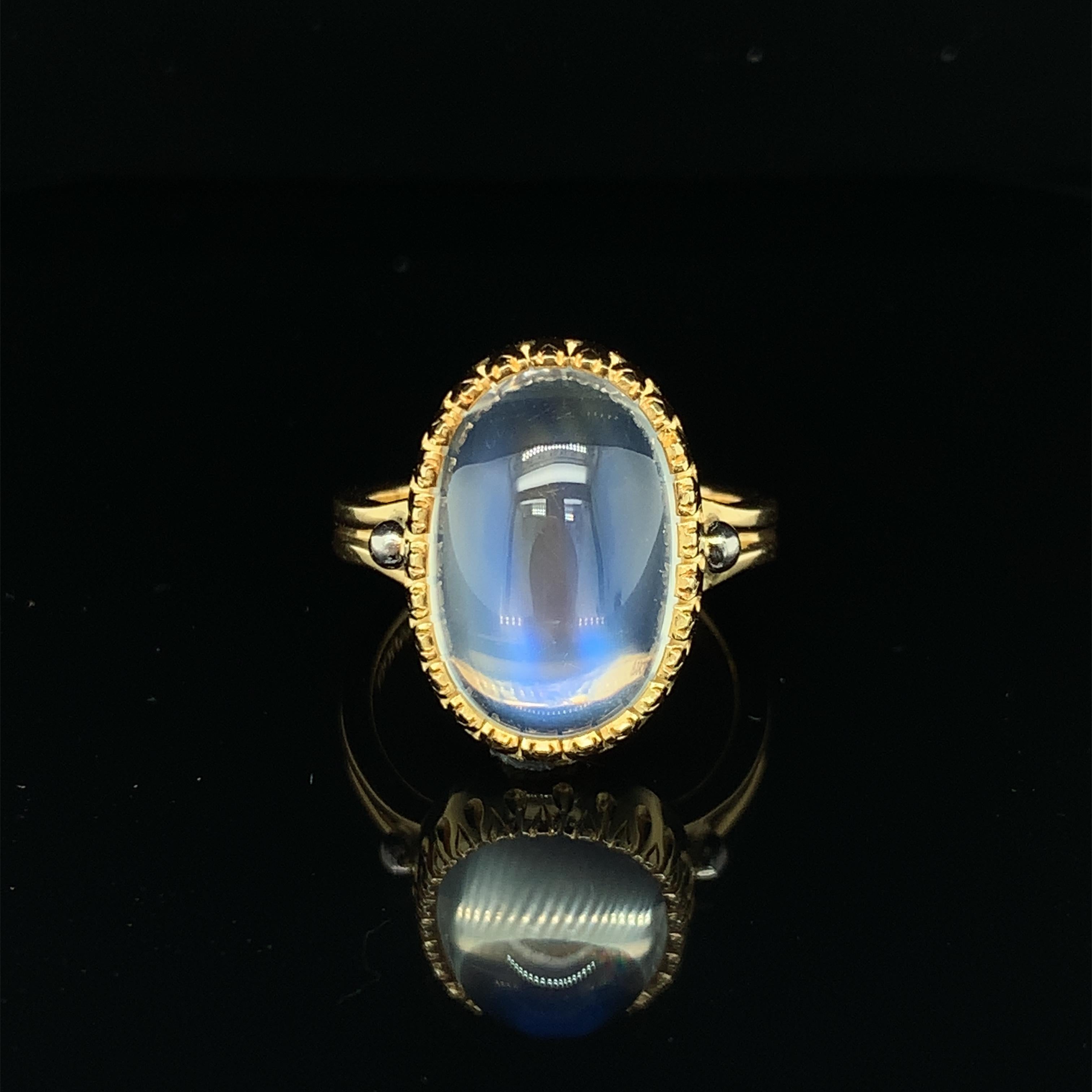This beautiful, 18k yellow gold handmade ring features a remarkably transparent 9.79 carat oval moonstone cabochon with gorgeous blue flash adularescence. Adularescence, or 