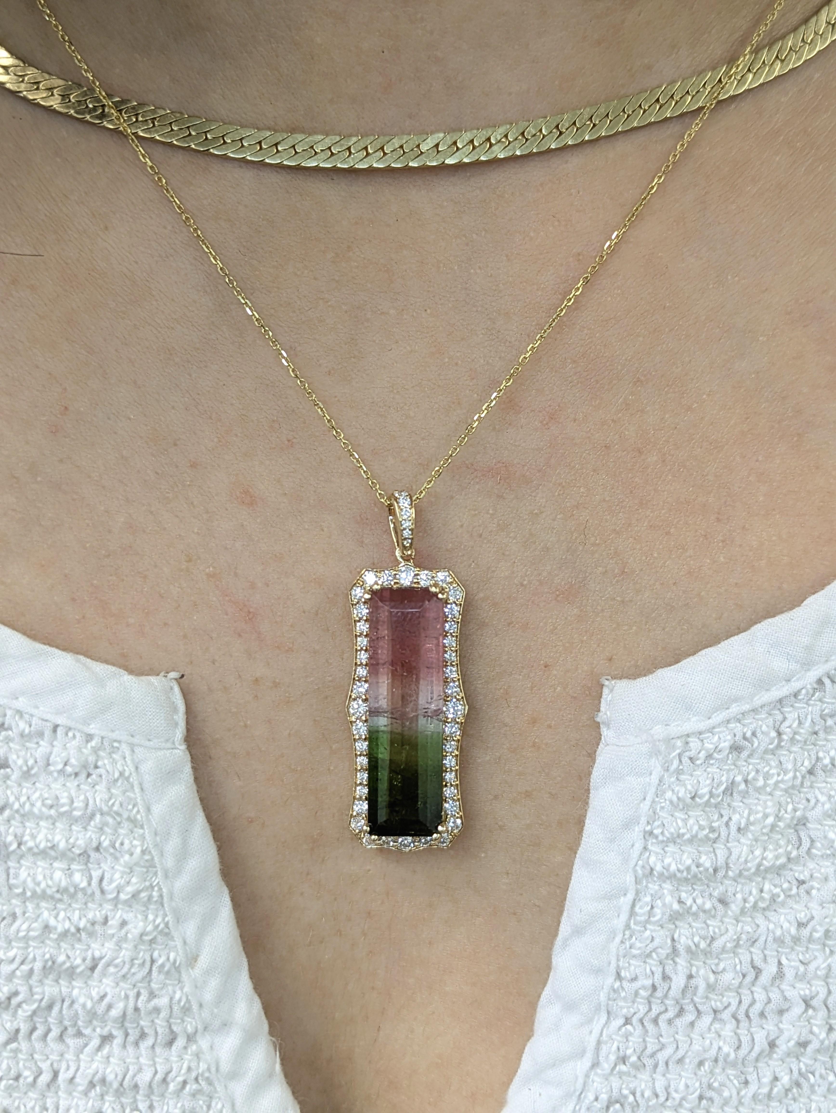 Audacieux et magnifique, ce grand pendentif en tourmaline melon d'eau brésilienne de 9,7ct se distingue par ses dimensions de 27x8mm. Entouré d'un halo étincelant de diamants naturels et serti dans un riche or 14 carats, il s'agit d'une pièce