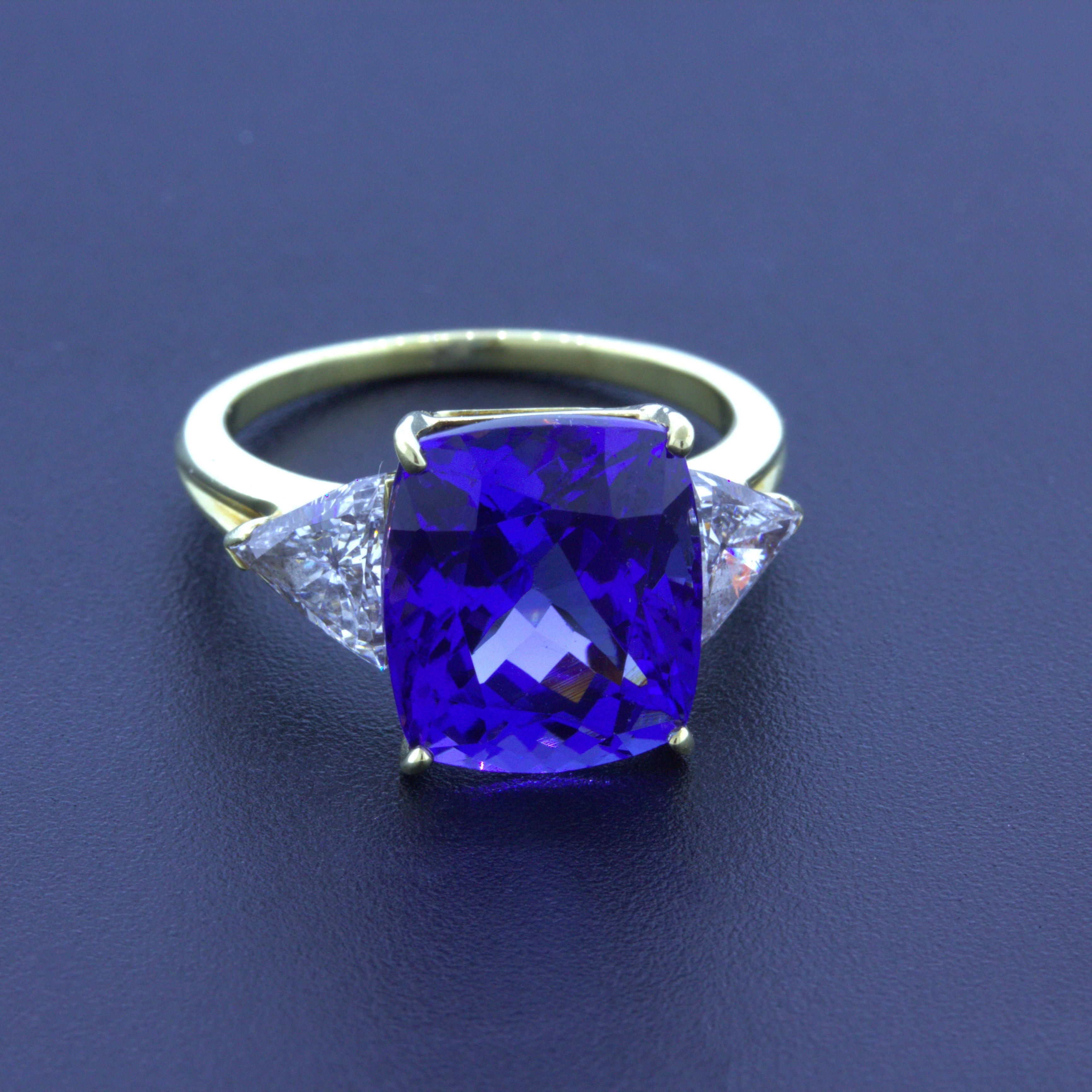 A chic and classy 3-stone ring that will stand the test of time! It features a beautiful 9.80 carat cushion-shape tanzanite which has a velvety purple-blue color with excellent brilliance and sparkle. It is complemented by two large triangular-cut