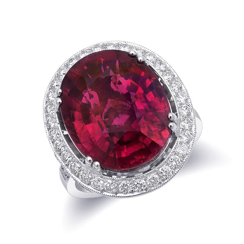 Perfectly deep red, the oval Rubellite that has been bezel-set in 18K White Gold with dazzling diamonds makes a Statement. This beautiful and very rare eye clean gem weighing 9.81 carats has been mined in Brazil. With filigree work at the bottom of