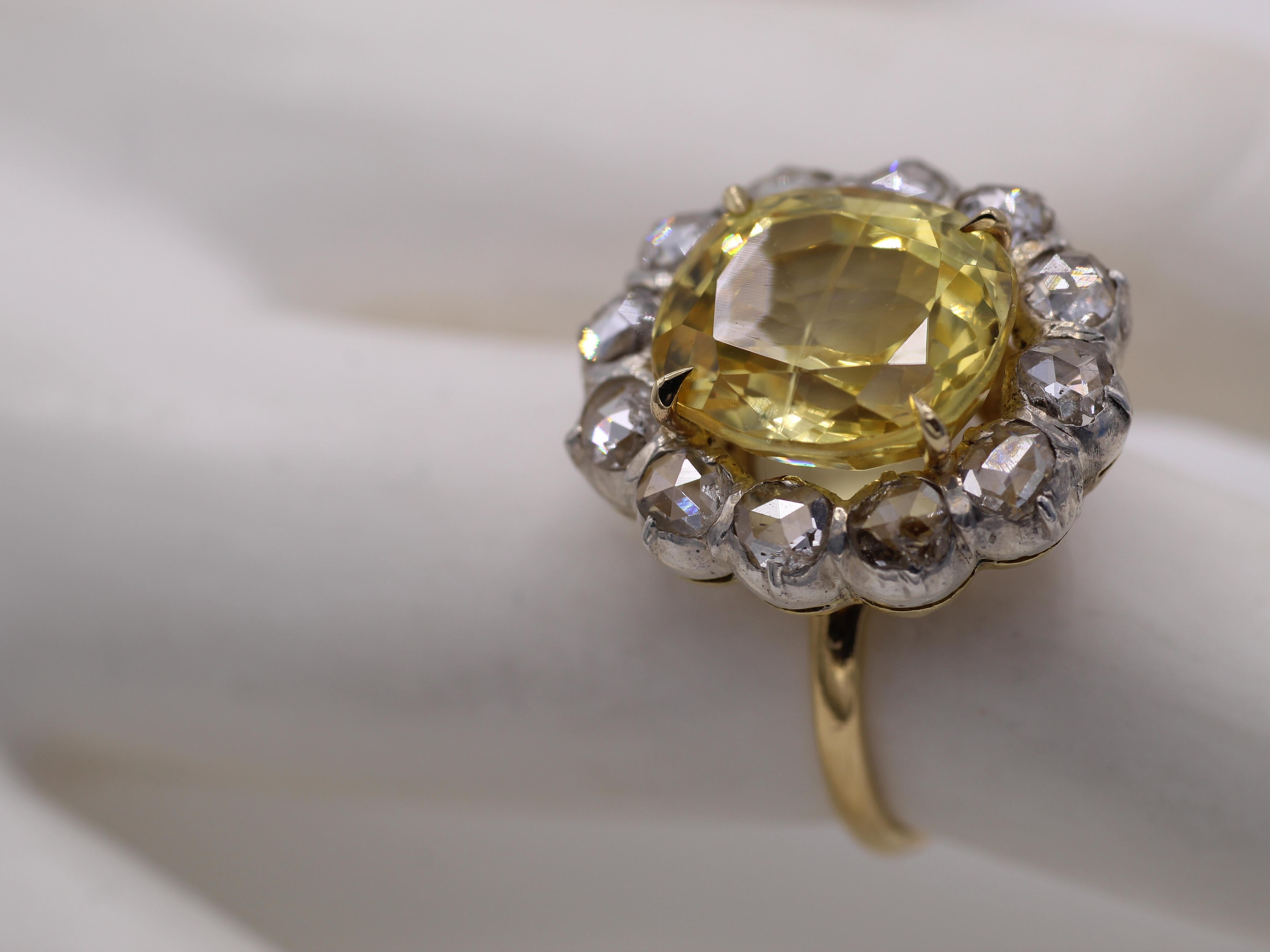 A wonderful lemon yellow oval natural no-heat yellow sapphire is the center piece of this beautiful and well handcrafted ring. Surrounded by a ring of rose cut diamonds set in silver on a gallery of yellow gold, this ring brings about a wonderful