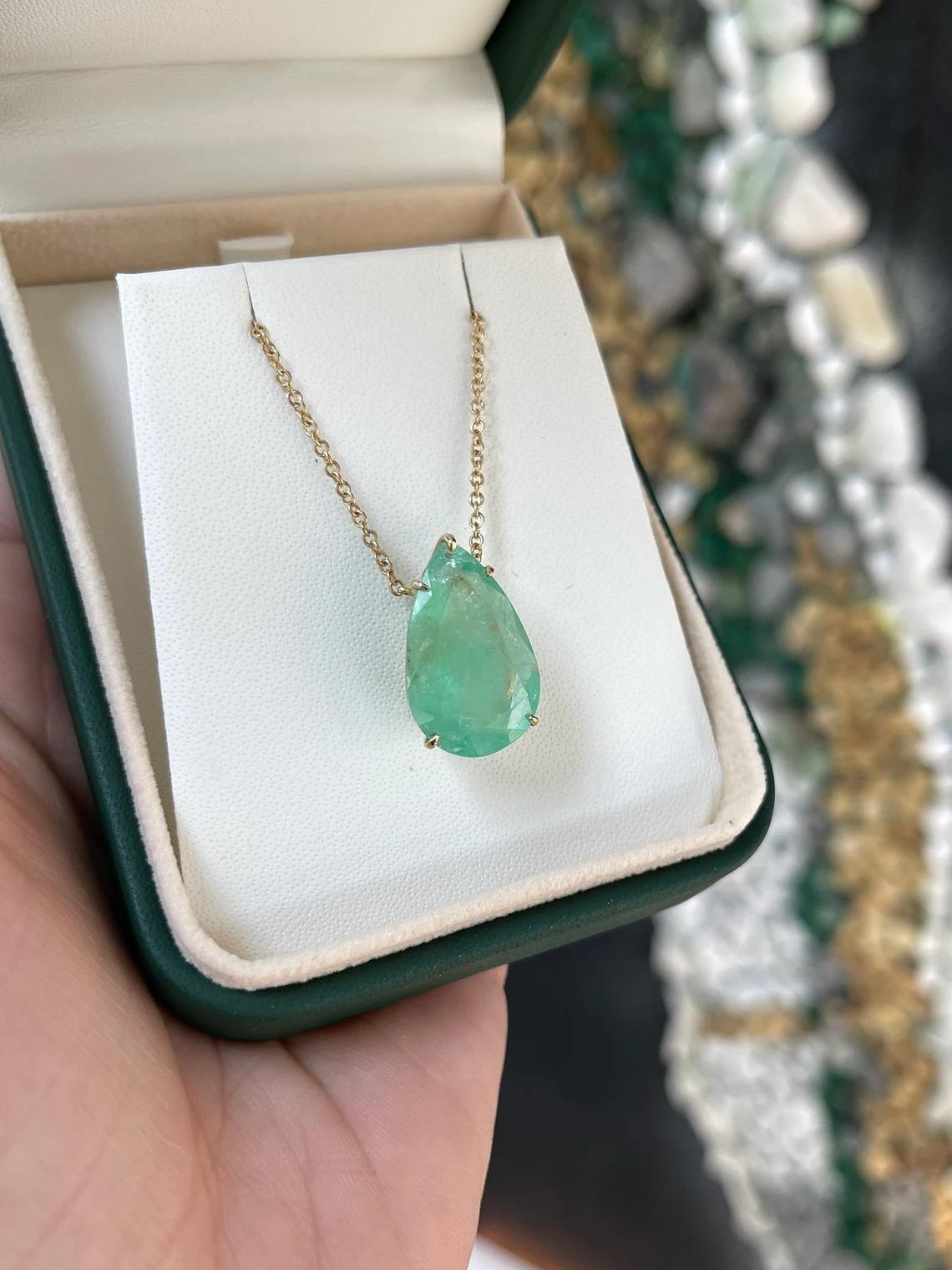 Displayed is a classic Colombian emerald solitaire necklace set in 14K yellow gold. This gorgeous solitaire piece carries a massive, natural Colombian emerald in a five-prong setting. Fully faceted, this gemstone showcases great shine. The emerald