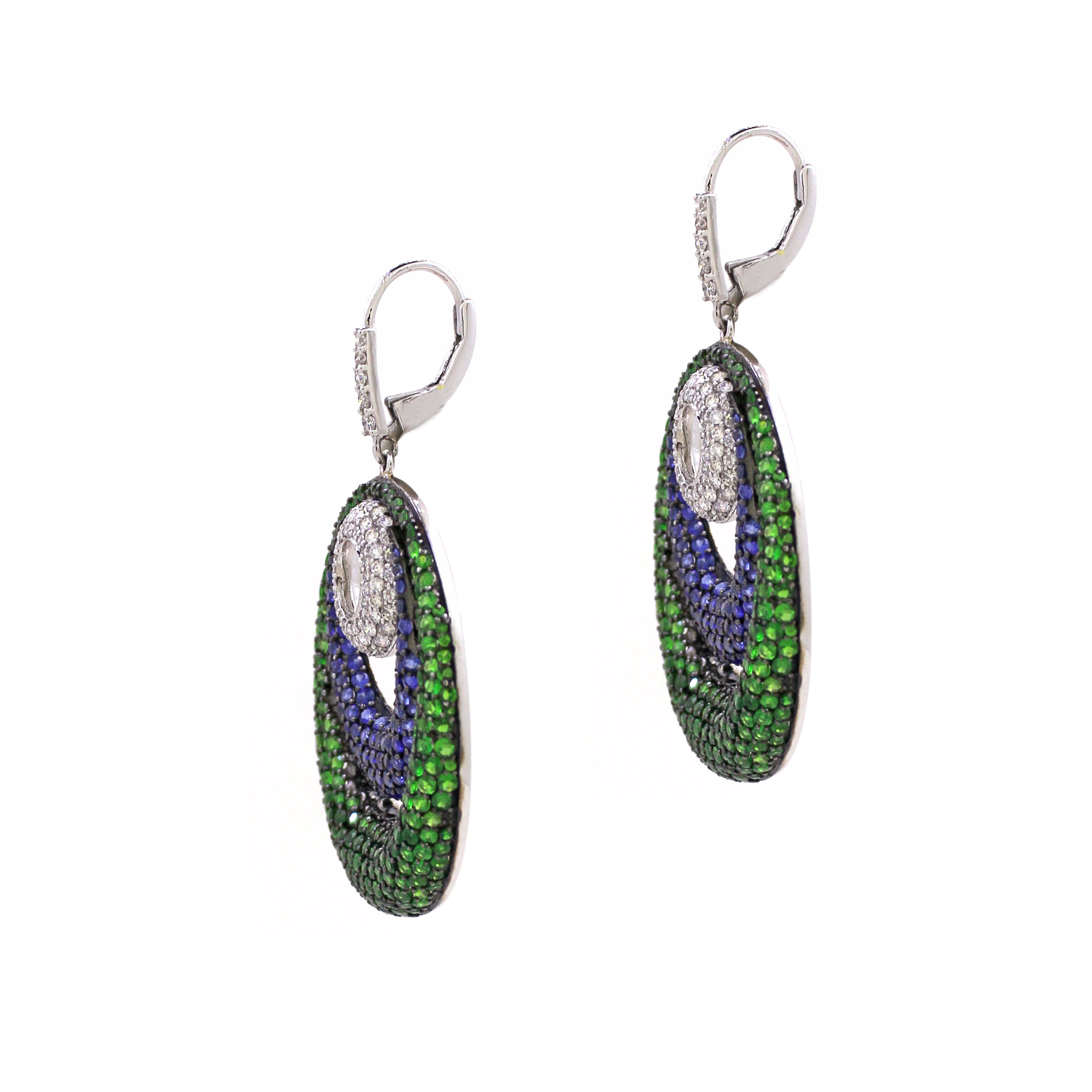 Ti presentiamo i nostri squisiti orecchini a goccia ovali, un mix straordinario di colori vivaci e design elegante. Questi straordinari orecchini presentano 390 tsavoriti per un totale di 6,52 carati e 178 zaffiri blu per un totale di 3,36 carati,