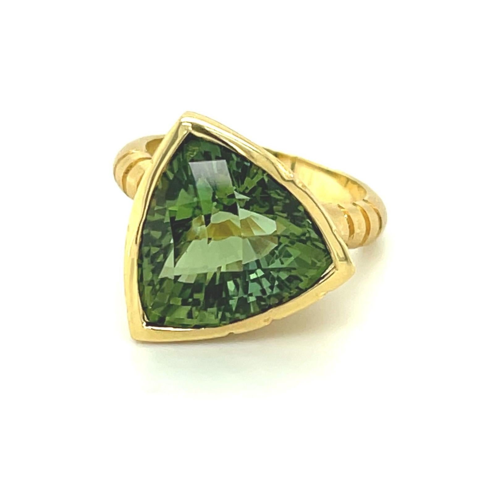 This bold, modern ring was custom-made in 18k yellow gold to showcase a gorgeous, custom cut green tourmaline. The center gemstone is a 