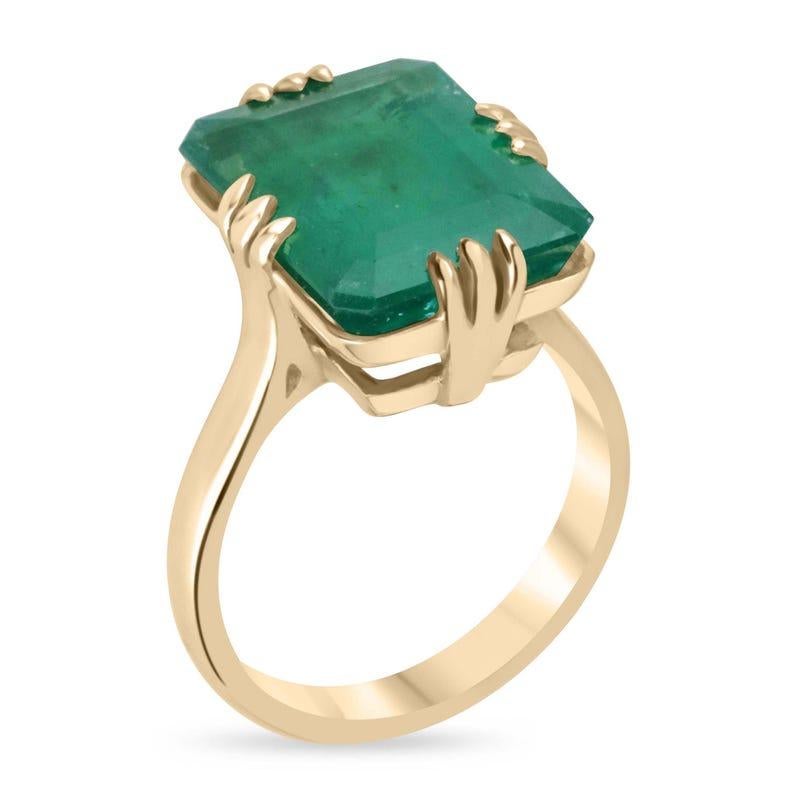 Introducing a bespoke Brazilian emerald vintage-inspired solitaire ring, custom crafted in luxurious 18K yellow gold. This breathtaking piece features an impressive 9.95-carat Brazilian emerald, secured in a unique twelve-prong claw setting that