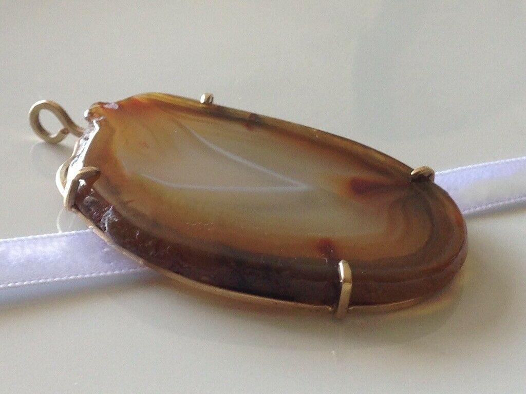 9ct 375  Gold - Large scottish natural agate slice Pendant
The 9ct gold surround is handmade
Stamped 9ct on rim
Slice  has an internal inclusion to the base of the white V
 - it can be felt when finger is rubbed across not dissimilar to a