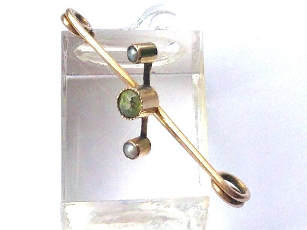 9ct 375 Gold Antique Safety Pin
Decorated with two seed pearls and a central green citrine
All components are 9ct gold including Pin
Stamped 9ct on pin
Length 3.5cm 
Total Weight 1.37 grammes .
