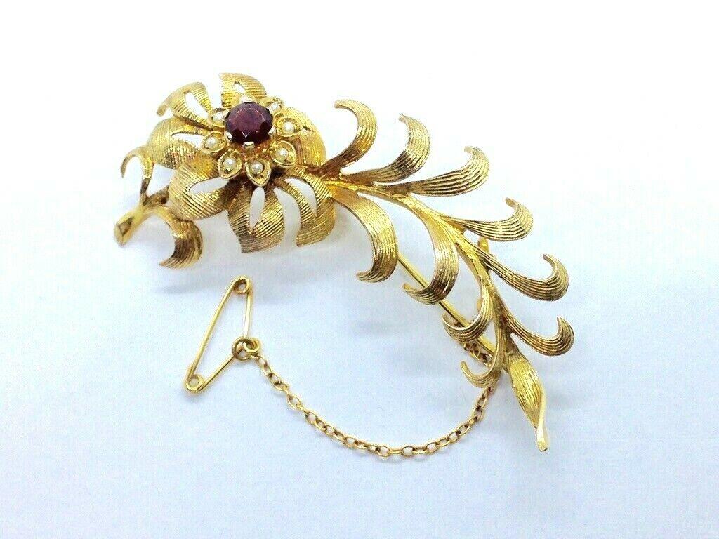 9ct 375 Gold Vintage Brooch with 
Unknown Burgundy Gem & Genuine Seed Pearls 
Beautifully decorative floral design
Genuine seed pearls are set in leaves surrounding the Gemstone
Actual Size 5cm x 2cm at widest points
Weight 7.46 grammes
Fully