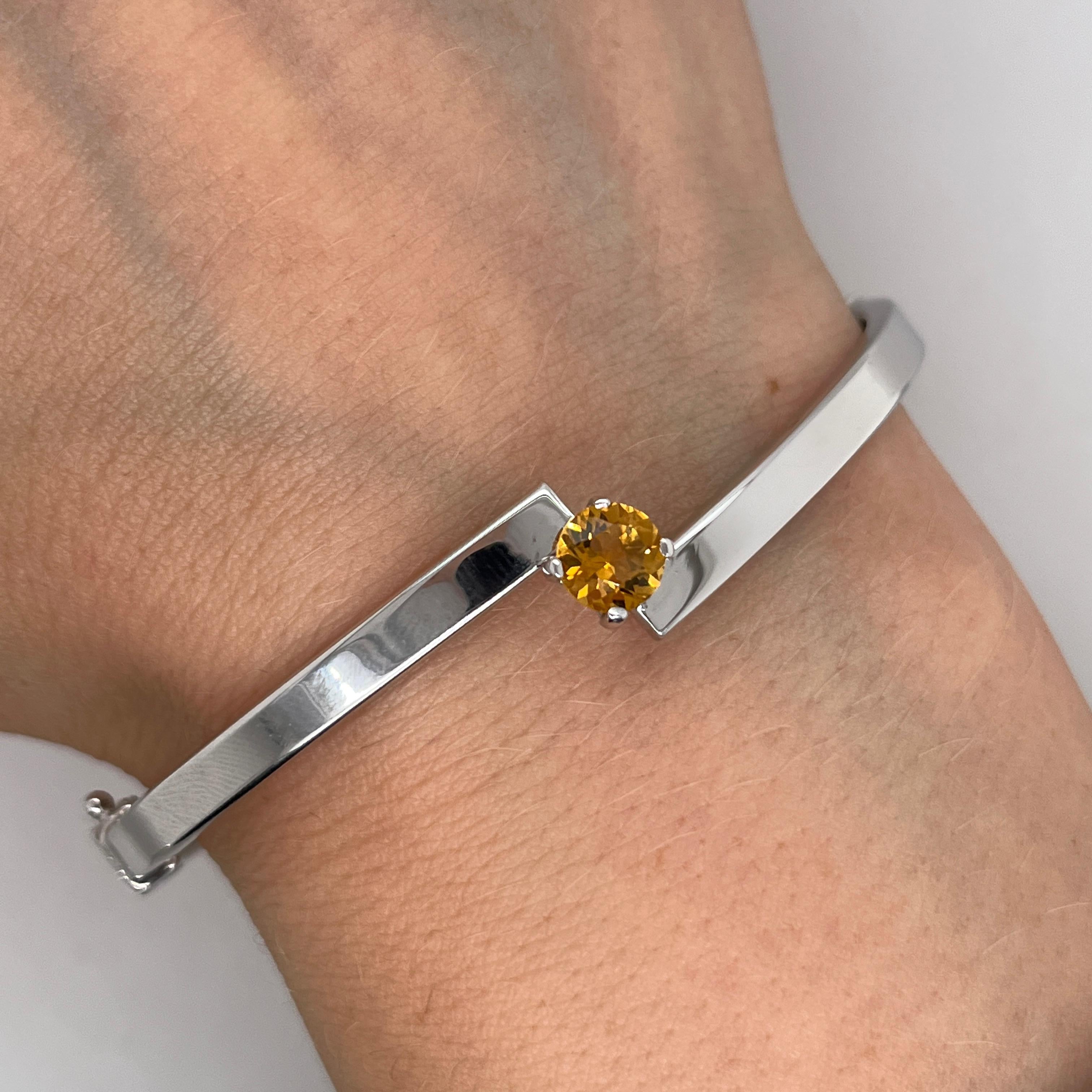 Questo braccialetto, elegante e moderno, è realizzato in oro bianco 9ct, con una vibrante gemma citrina al centro. La calda tonalità dorata del citrino contrasta meravigliosamente con i toni freddi dell'oro bianco, creando un accessorio di grande