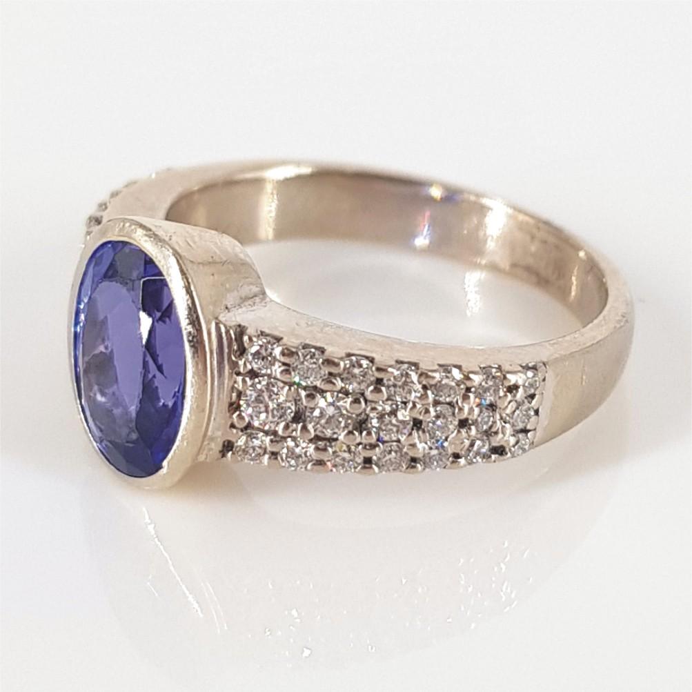 This beautiful sophisticated ring is set in 9 Carat White Gold and weighs 5.5 grams. It features 1 1.90 carat Oval Cut Tanzanite at the Center with 40 RBC Diamonds on the sides carrying a total carat weight of 0.44. The ring size is an L.