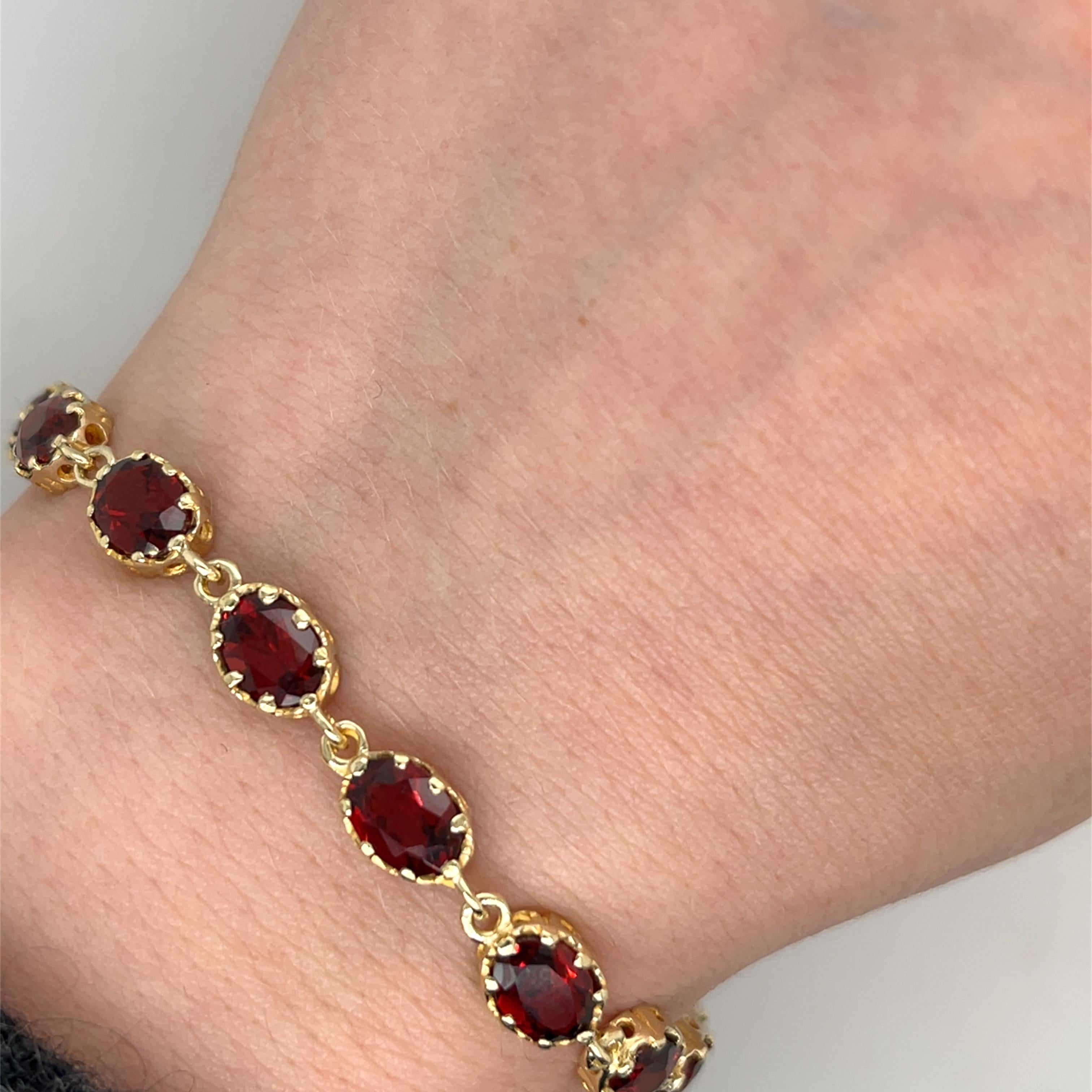 A stunning vintage 9ct yellow gold bracelet, elegantly 
set with 16 natural oval-cut garnets, each displaying a deep, rich red hue. This timeless piece exudes classic charm and sophistication, making it a perfect addition to any fine jewellery
