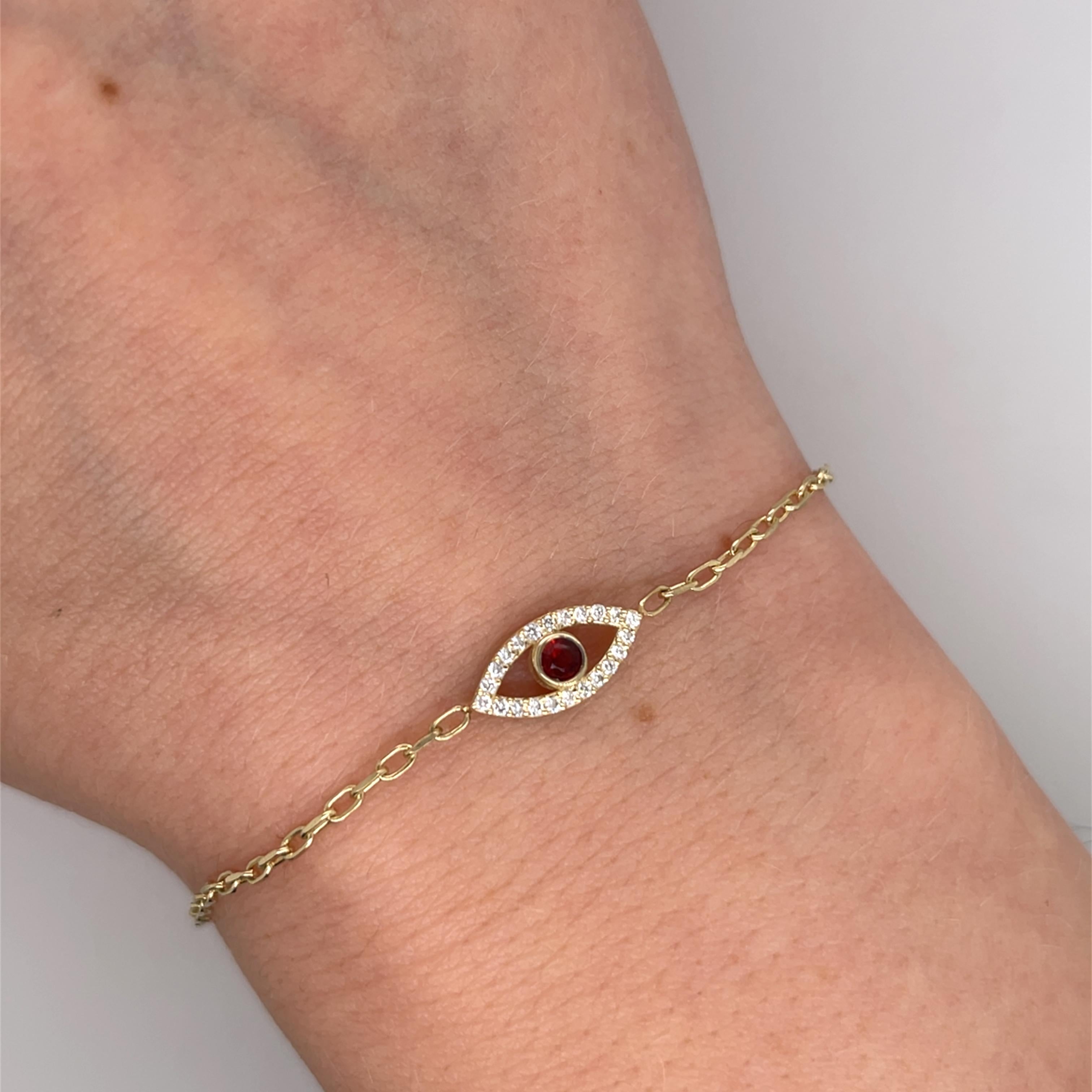 Un étonnant bracelet en or jaune 9ct pour le mauvais œil, 
dont la pièce maîtresse est un grenat rouge foncé, la pierre de naissance du mois de janvier. 
Le grenat est encadré dans un dessin symbolique pour la protection et la bonne fortune.

Poids