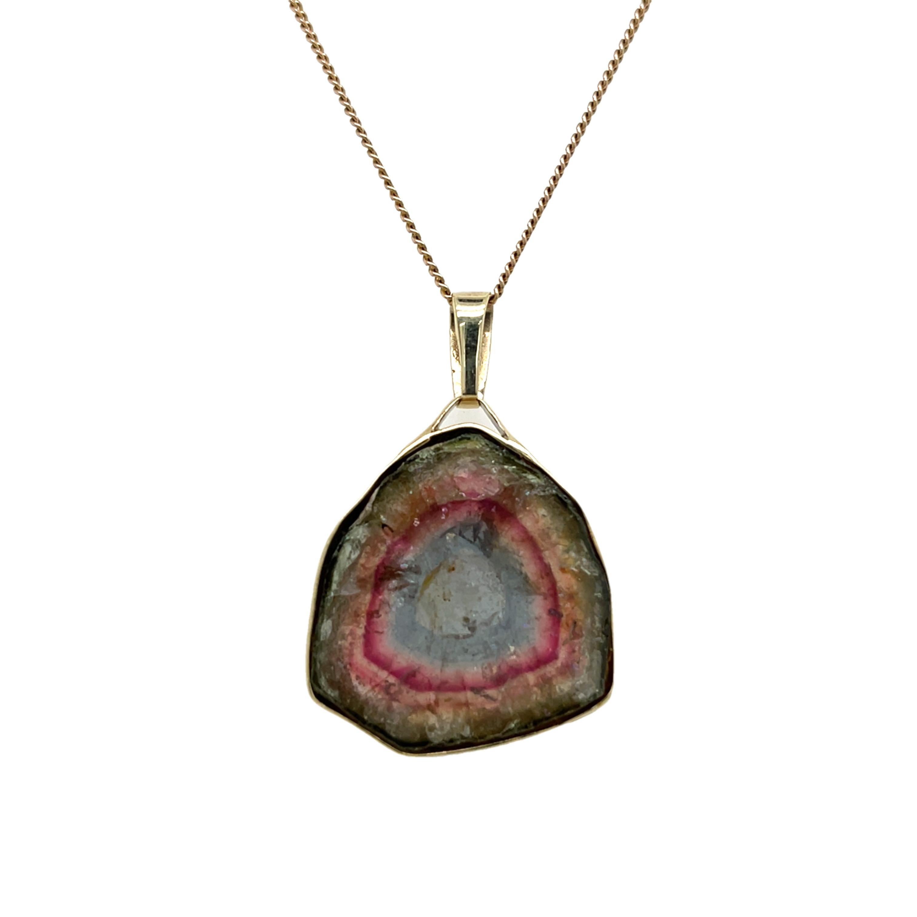 Questo elegante ciondolo presenta una splendida gemma d'agata multicolore, che mostra vortici naturali di tonalità vibranti, incastonata in una collana d'oro a 9 carati. Perfetta per aggiungere un tocco di colore a qualsiasi abbigliamento, questa