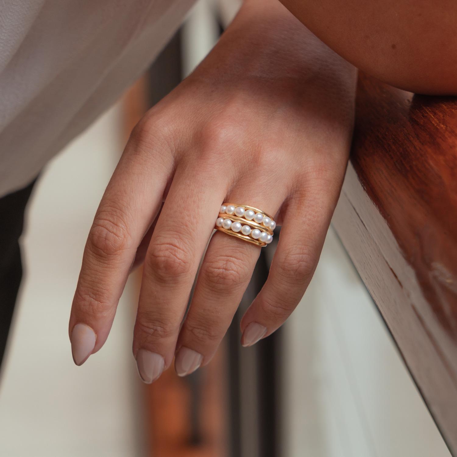 A bold organic style Waterfall 9k white gold ring, with thirteen small white pearls in two rows of dots between three Ripple style outer bands. The ring is designed to evoke the purity of fresh morning dew. The ring tapers from 12mm at the widest,