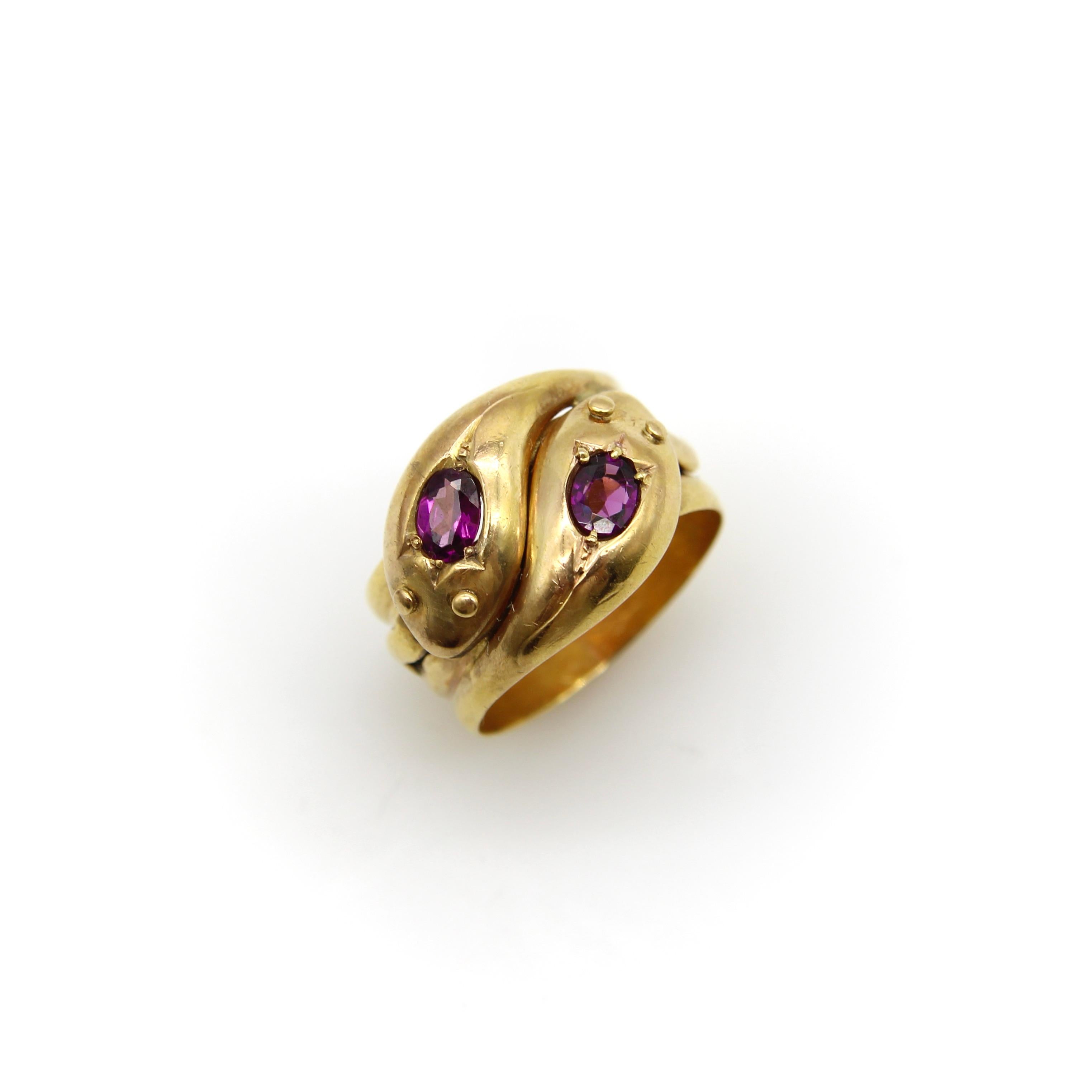 This is a classic 9k gold snake ring that has two beautiful rhodolite garnets in the head of each snake. The snake heads interlock   and the garnets are bead set into a mount that are carved to look like tulips. The oval rhodolite garnets are a deep