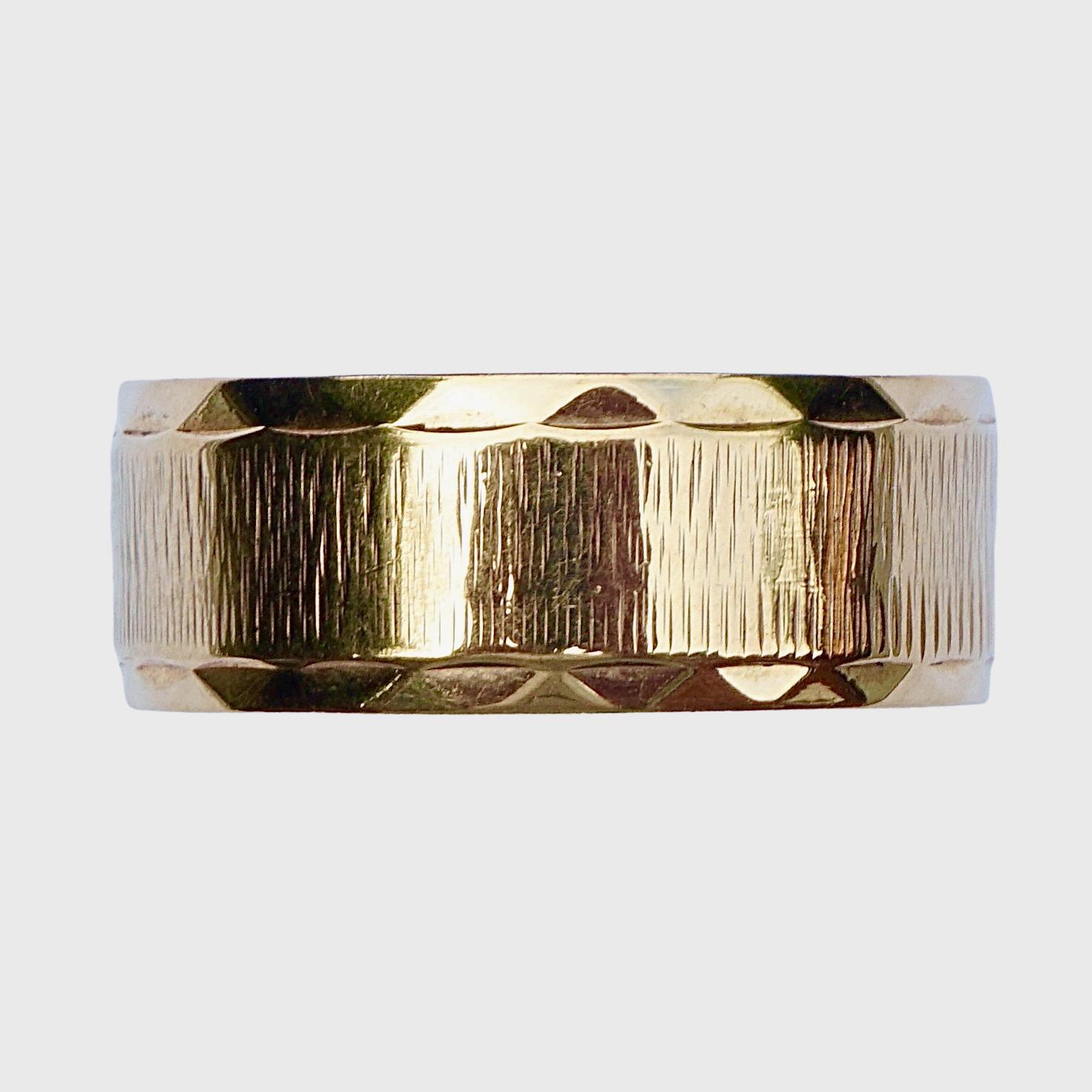 Splendido anello a fascia in oro giallo 9K, con disegno di corteccia inciso e bordi fantasia.

L'anello presenta marchi inglesi per l'oro 9K, una testa di leopardo per l'ufficio di saggi di Londra e la lettera della data è 