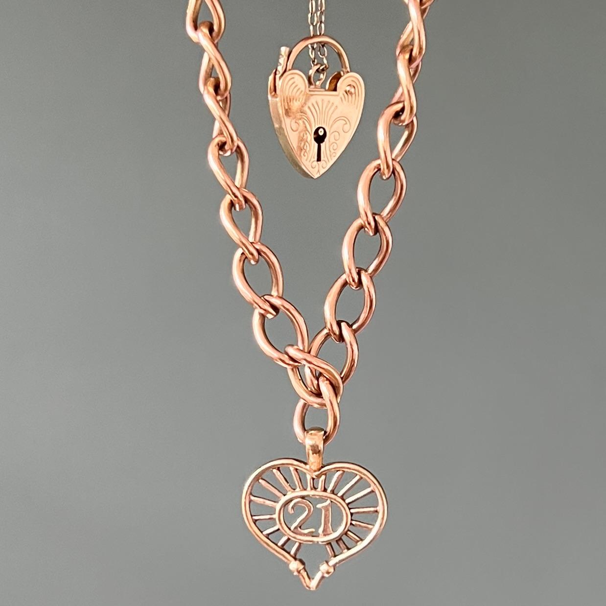 A padlock charms bracelet set with two lovely hearts. The curb chain and hearts are made of 9 karat gold with a soft pink tone. The heart-shaped padlock has beautiful engravings on the front and is fitted with a safety chain. 
The large heart-shaped