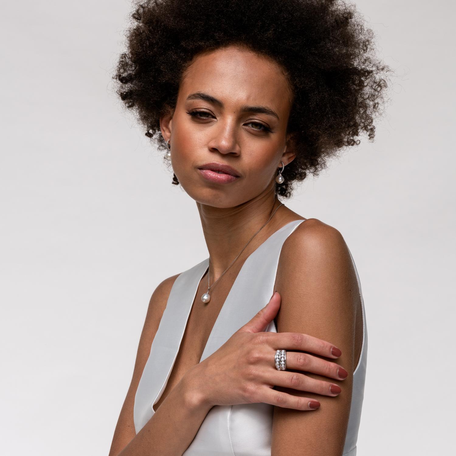 A bold organic style Waterfall 9k white gold ring, with thirteen small white pearls in two rows of dots between three Ripple style outer bands. The ring is designed to evoke the purity of fresh morning dew. The ring tapers from 12mm at the widest,