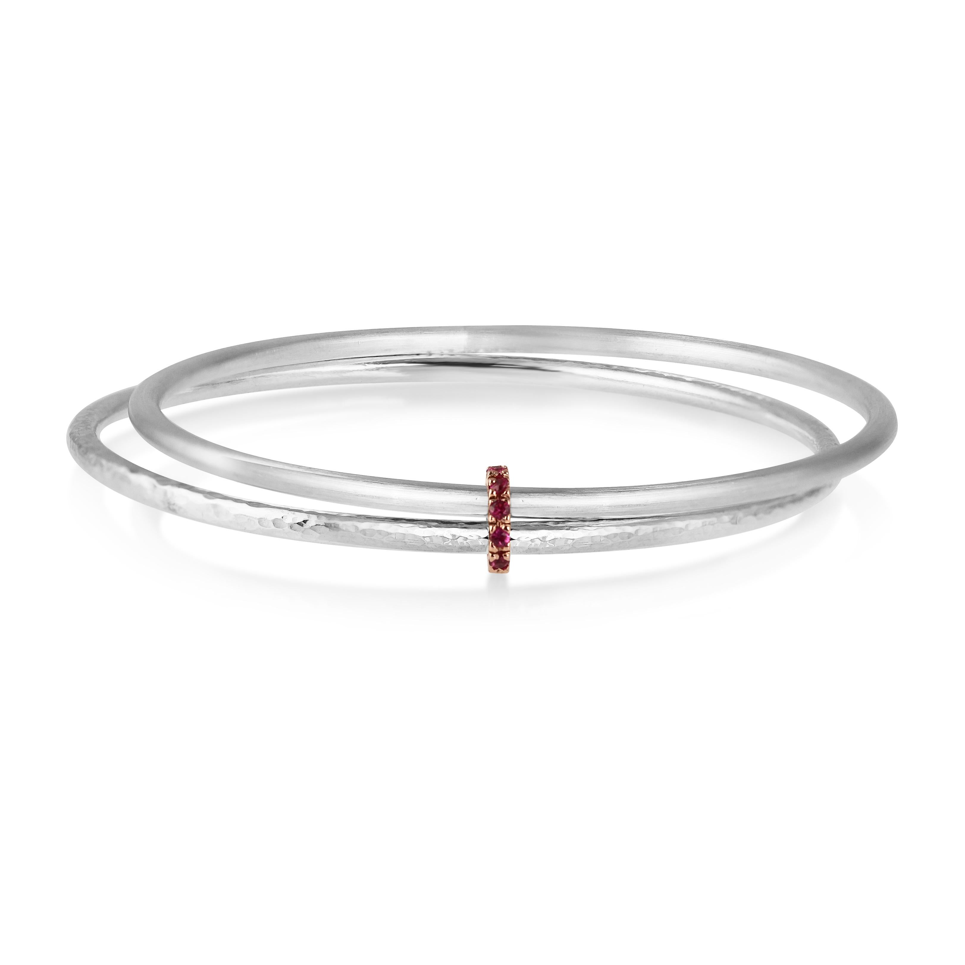 Twin 9 karat white gold bangles, both the same and yet different. The one a shimmering hammer finish, the other a smooth satin texture. Bound together, always, by rose gold & pink rubies.

Ruby's are know as the 'King of Gems' and represent love,