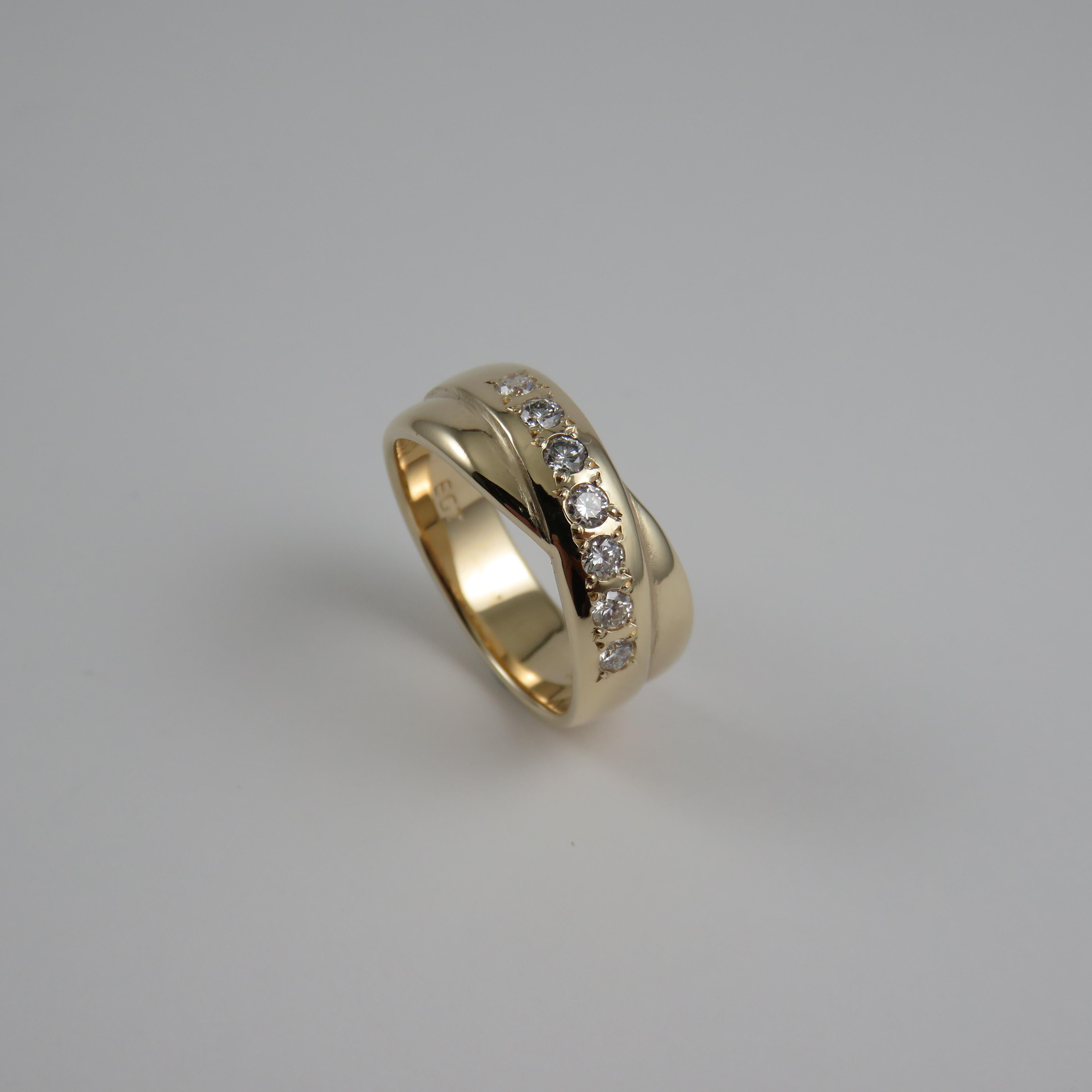 This is a 9k yellow gold eternity ring with a 8mm wide cross-over design, and semi-Russian style featuring seven round brilliant cut diamonds (measuring 2.35-2.4mm) and totaling 0.35 carats that are grain set for a close, secure hold.  The ring has