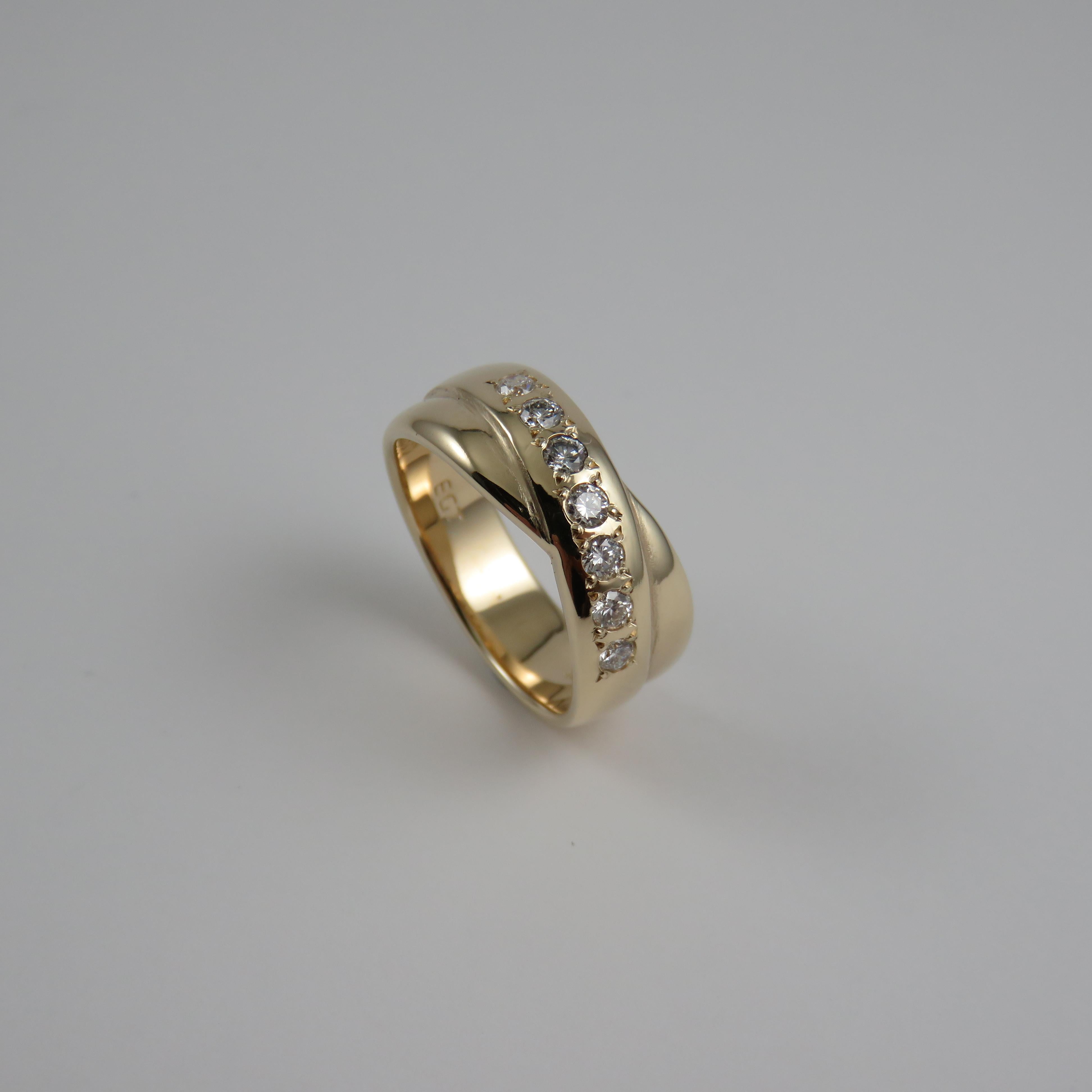 Dies ist ein Ewigkeitsring aus 9kt Gelbgold mit einem 8 mm breiten Cross-Over-Design und halb-russischem Stil mit sieben runden Diamanten im Brillantschliff (2,35-2,4 mm) und insgesamt 0,35 Karat, die für einen engen, sicheren Halt mit Körnern