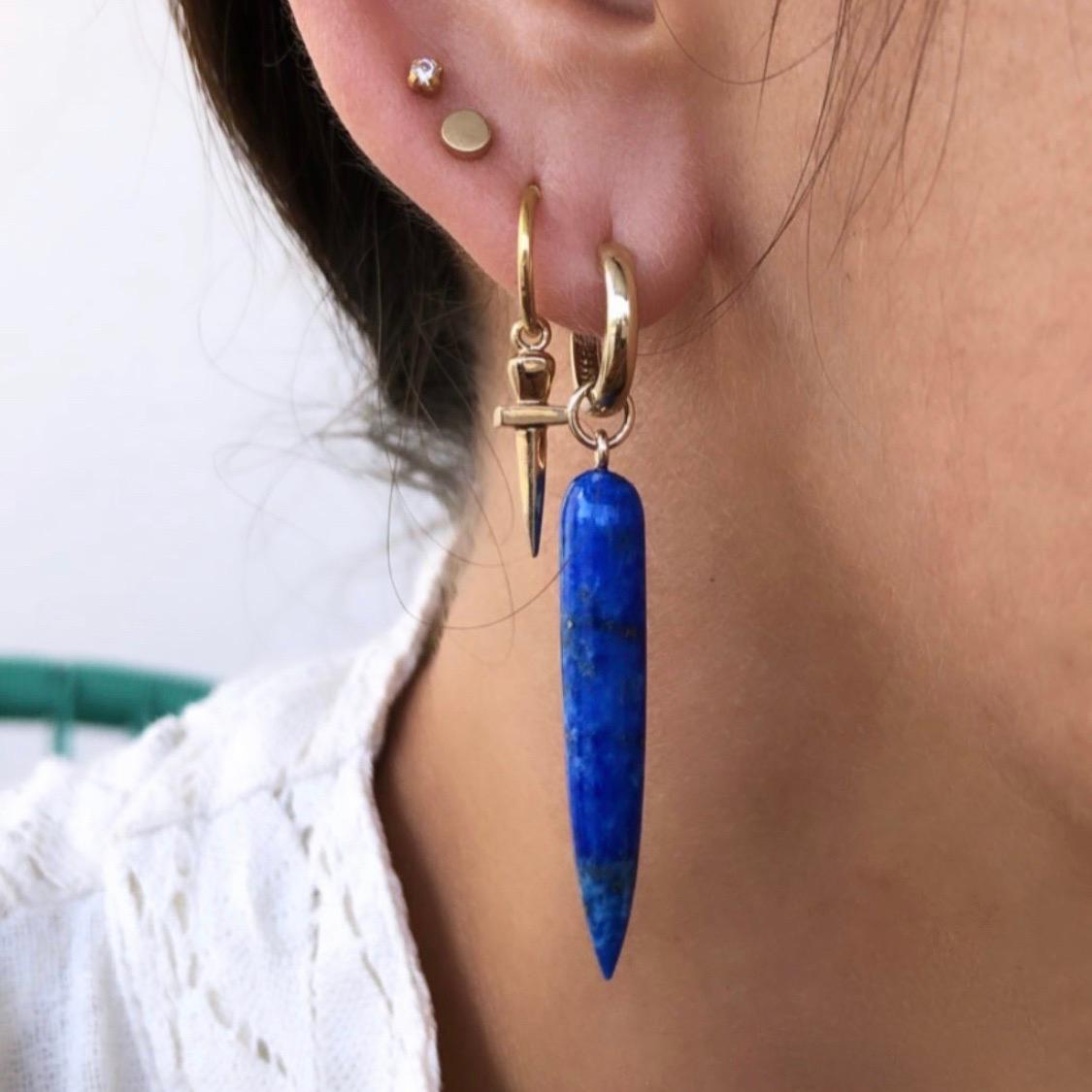 Add a touch of elegance and serenity to your look with these Solid 9k Yellow Gold Lapis Long Spike Huggie Drop Earrings. These earrings feature a stunning combination of lapis lazuli and yellow gold, creating a timeless and sophisticated